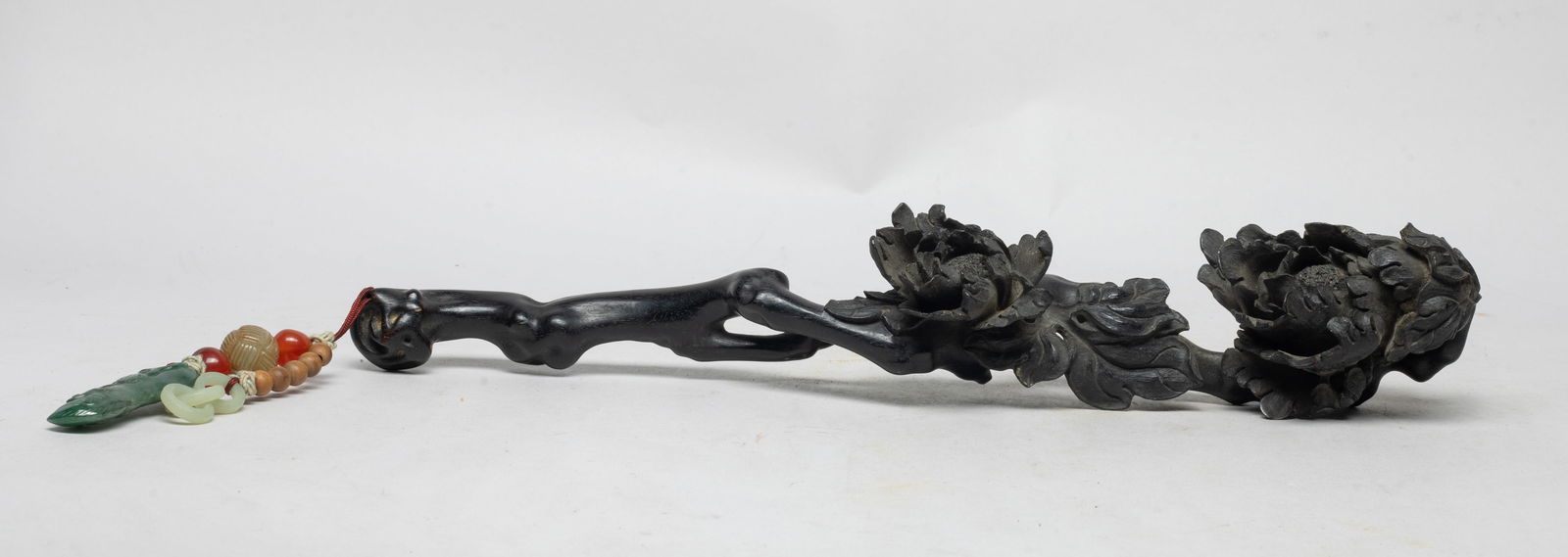 Chinese Zitan Wood Ruyi w/ Jade Pendant: The wood scepter deeply undercut as a gnarled leafy branch issuing large blossoming flowers, suspended with seed, stone and jade beads, jade / stone loops, and a peapod form jade pendant. Approx. 13.1