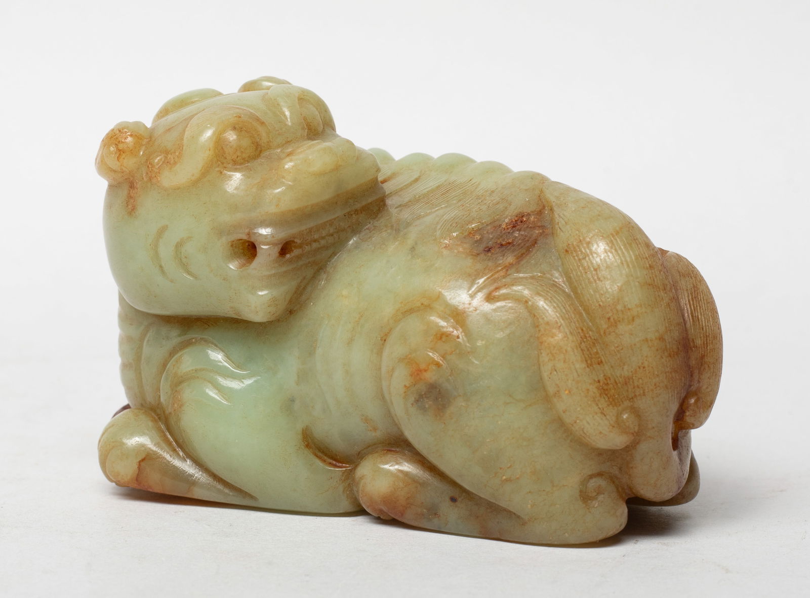 Estate Chinese Russet Jade Sculpture of Beast: Finely carved in the round as a recumbent beast with its cub playfully resting on its back, the ridged spines extending to finely incised bushy tails, the stone of a pale celadon tone with russet incl