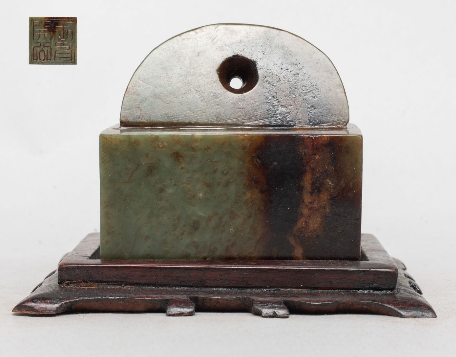 Large Chinese Jade Carved Seal: Chinese celadon and russet jade seal of square section, surmounted with a sloped and faceted finial drilled with a hole near the top, with a wood base. Approx. 2.6*2.6*2.5 inch (w/o stand).