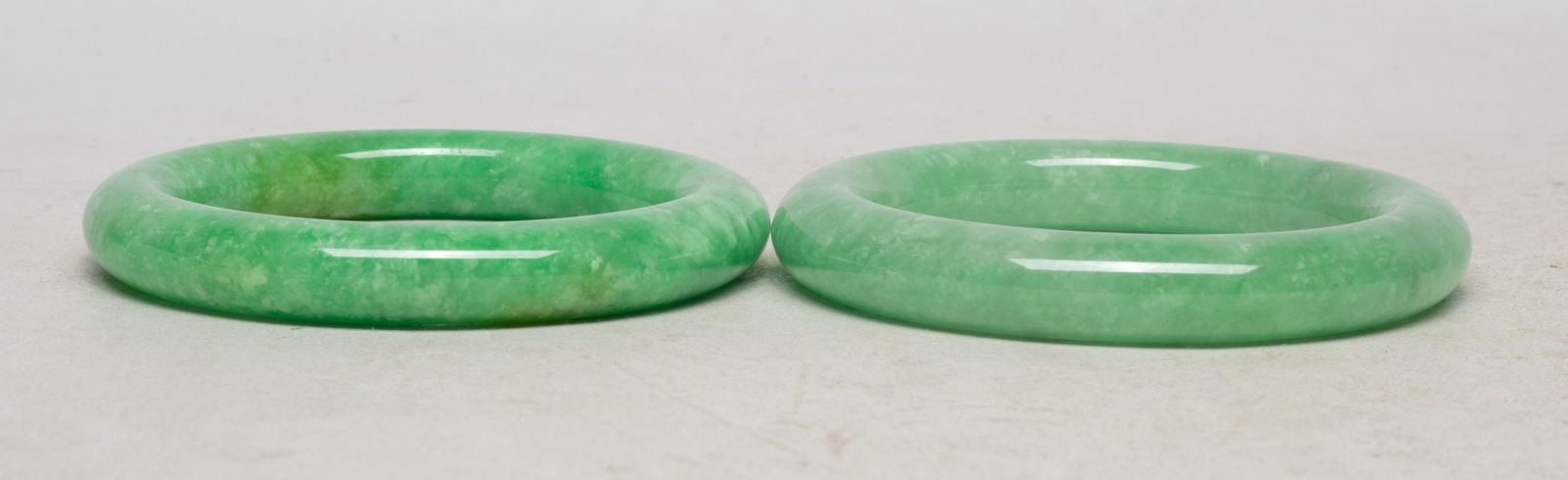 Two Chinese Export Jade/ Stone Bangles: Two Chinese jade / colored stone carved bangles. Approx. 3.25 inch outer diameter, 2.3 inch inner diameter (larger). The Estate of the Store Closed Sale, Hollywood, CA, 2019.