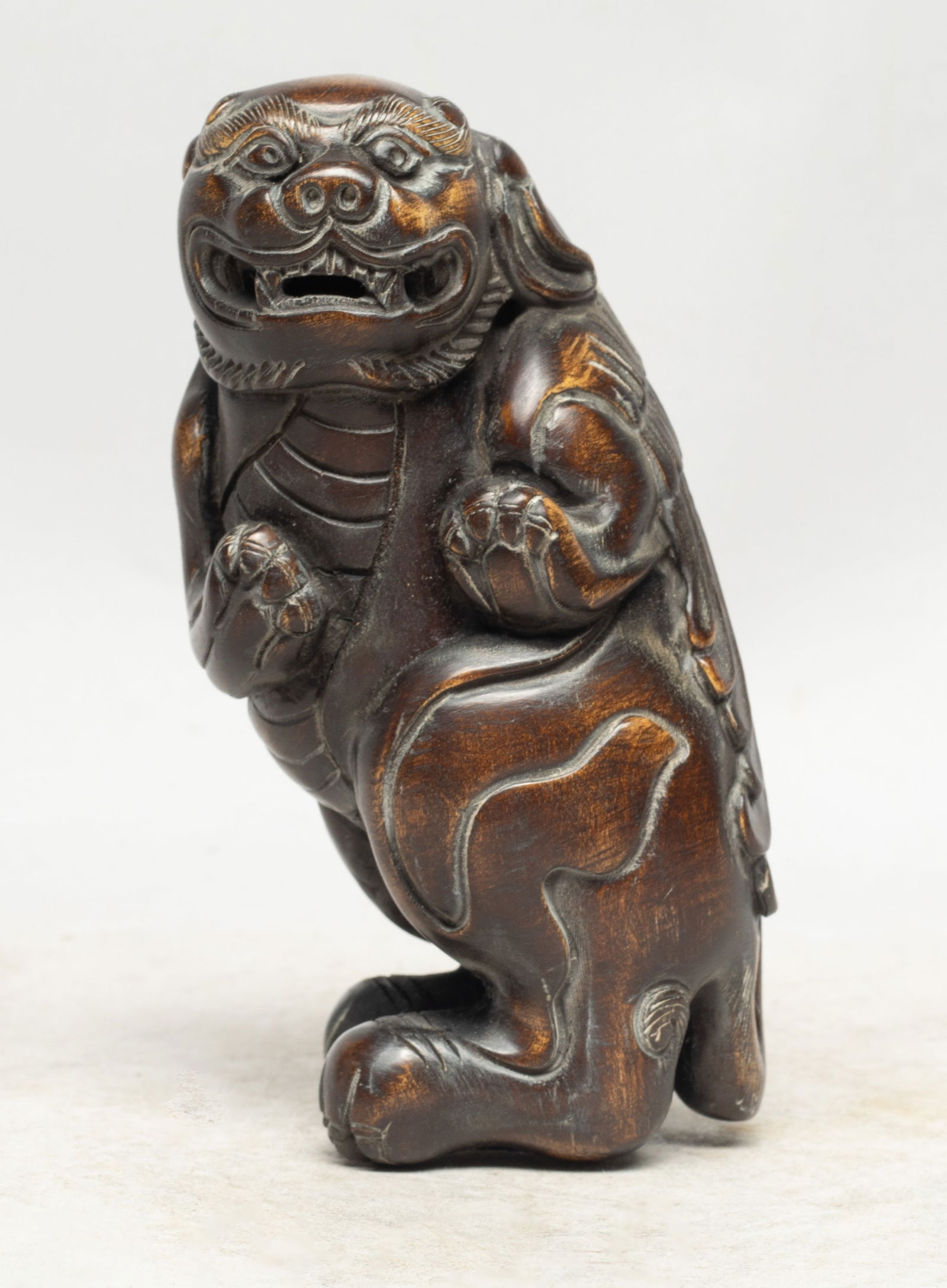 Collectible Chinese Wood Like Table Sculpture: Chinese wood-like sculpture carved of mythical beast form, the head turned to the left, with bulging eyes under bushy brows, and mouth agape baring its teeth. Approx. 5.3*2.5*2.3 inch.