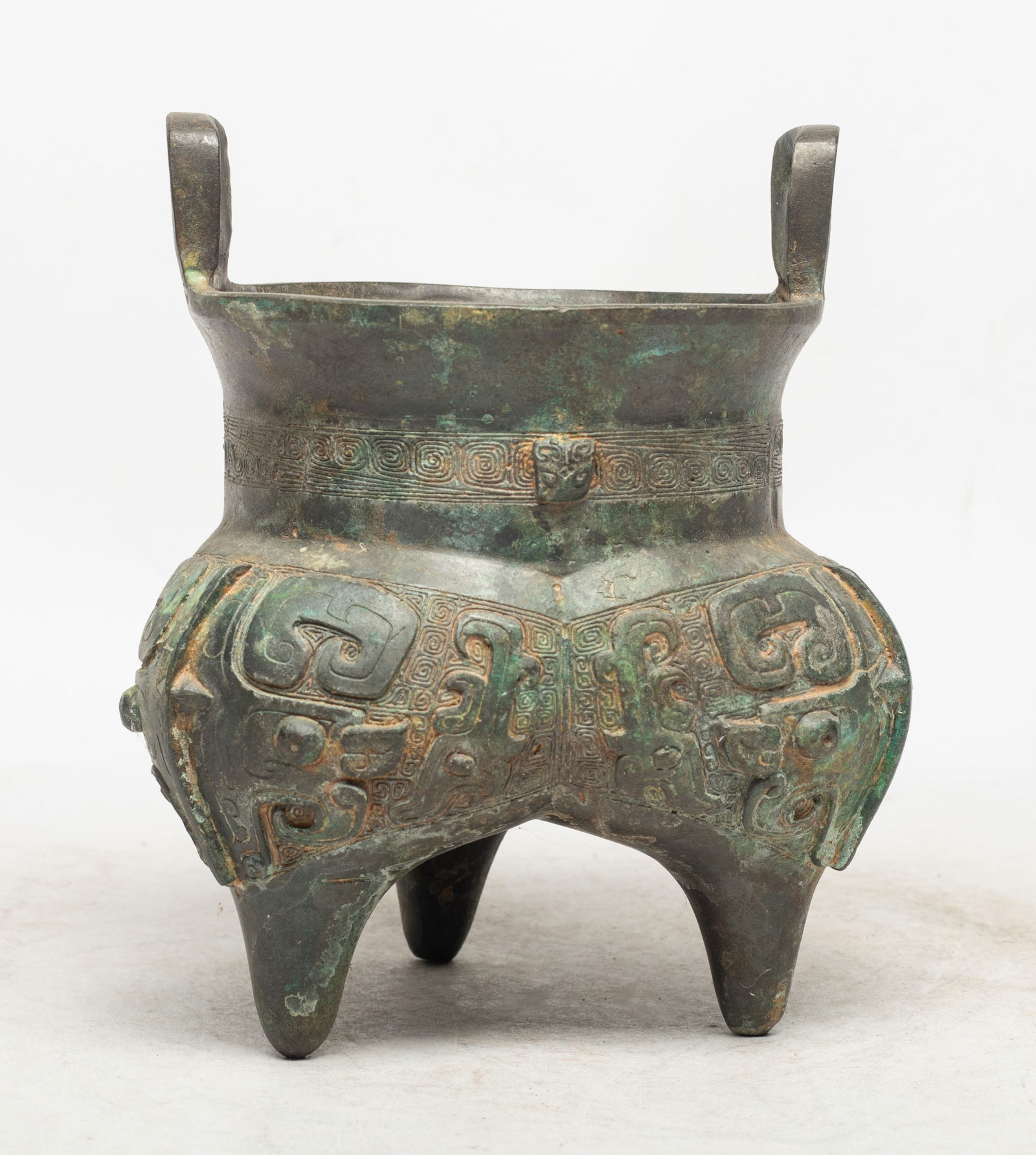 Estate Chinese Bronze Censer: Chinese archaic bronze tripod censer with two handles, cast with a taotie masks divided by flanges on leiwen ground, the bottom inscribed with two characters. Approx. 6.5*5.5 inch.