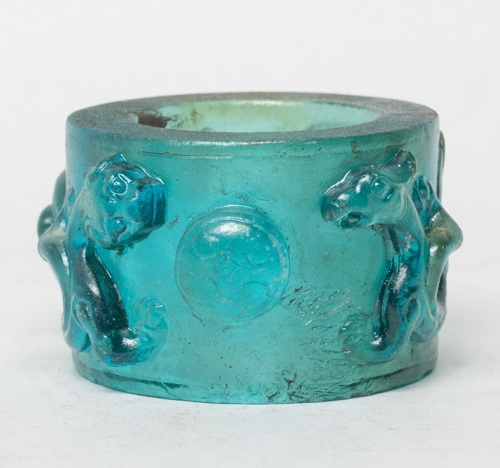 Rare Chinese Peiking Glass Thumb Ring: Chinese blue-green Peiking glass thumb ring, carved in high relief with a pair of sinuous beasts pursuing a ball. Approx. 1.7*1 inch.