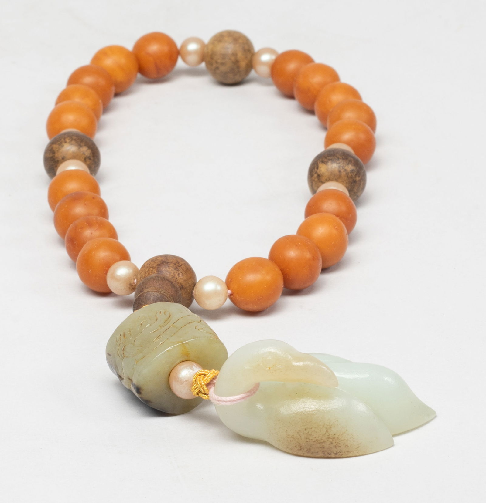 Chinese Manchu Amber, Jade Prayer Beads: A string of Chinese Manchu amber and agarwood carved prayer beads, with a large russet jade bead incised with a chilong, and a white and russet jade carved duck form pendant. Approx. 1.9*1.08*1 inch