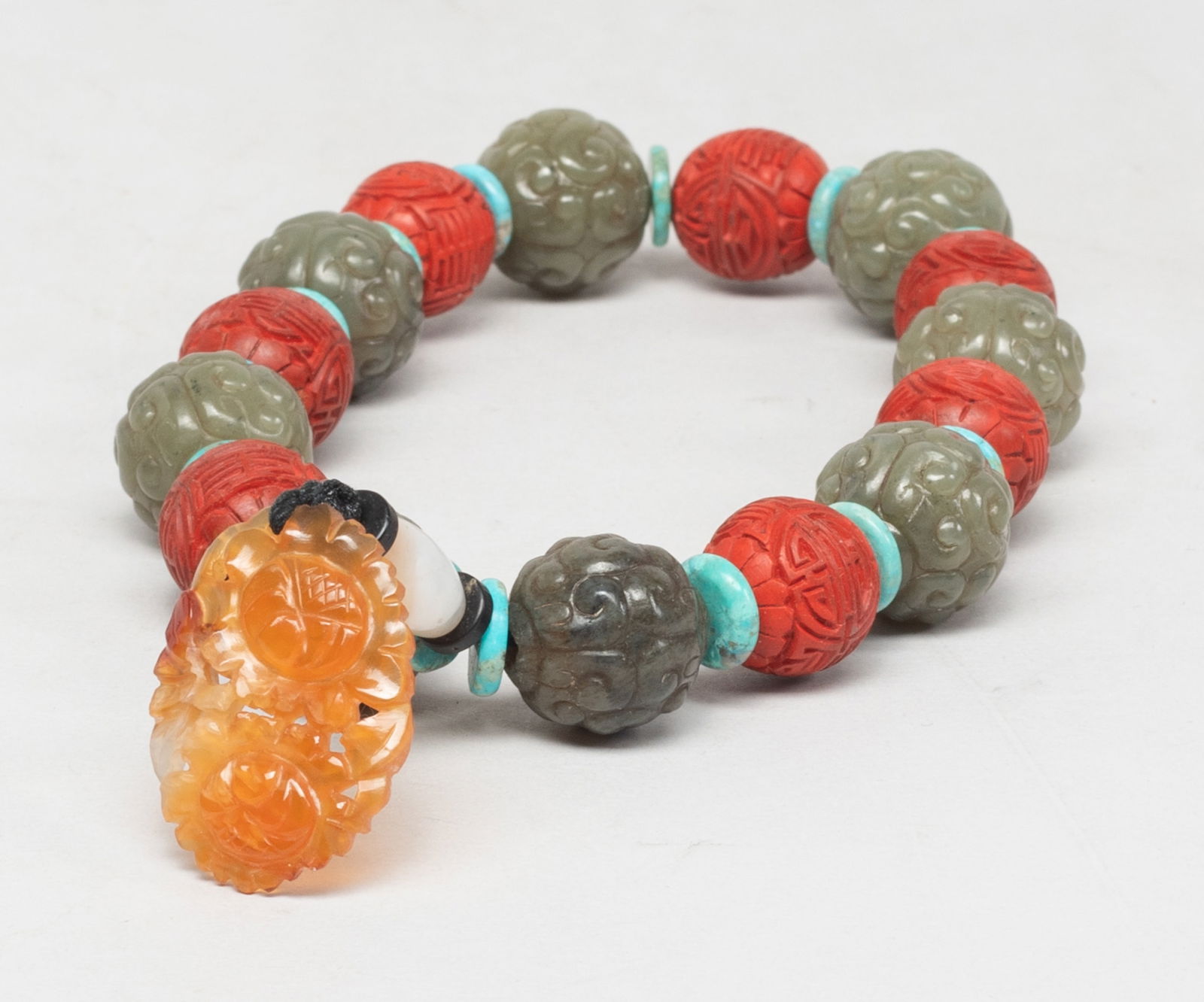 Rare Chinese Jade, Cinnabar Prayer Beads: A string of jade and cinnabar prayer beads, spaced by stone disc beads, the jade beads carved archaic scrolls and the cinnabar beads carved with flowers and shou characters, suspended with an agate