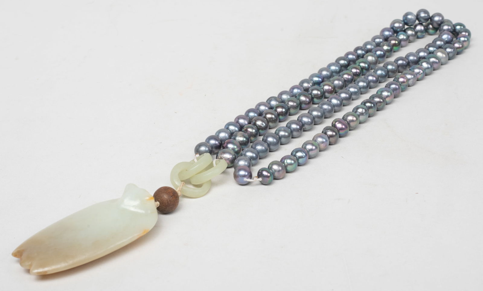 Chinese Export Pearl Necklace w/ Jade Pendant: Long Chinese pearl necklace, suspended with three interlocking jade / stone loops, a wood bead, and a russet jade carved cicada pendant. Approx. 30 inch L (necklace size). The Estate of the