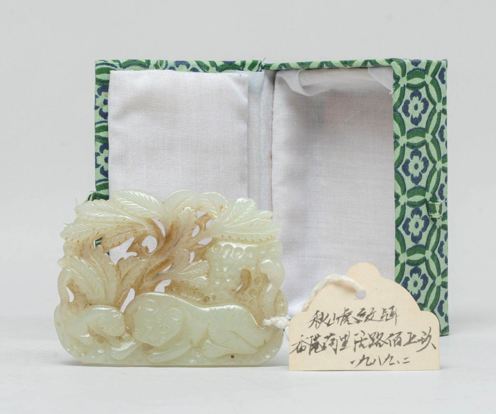 Estate Chinese Russet Jade Pendant: Carved in openwork with a recumbent tiger and its cub under leafy branches and rockery, with box. Approx. 2.7*2.05 inch (jade size). The Estate of E Los Angeles, CA, 2021.