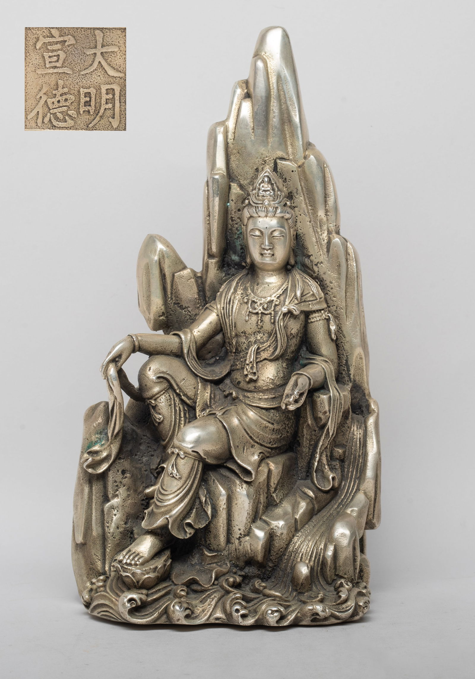 Collectible Chinese Bronze Sculpture of Kuanyin: Cast with full face and high ushnisha and attired in monastic robes, seated in the meditation posture on a mountain form throne with hands held in elegant mudra, the bottom inscribed with a four-chara