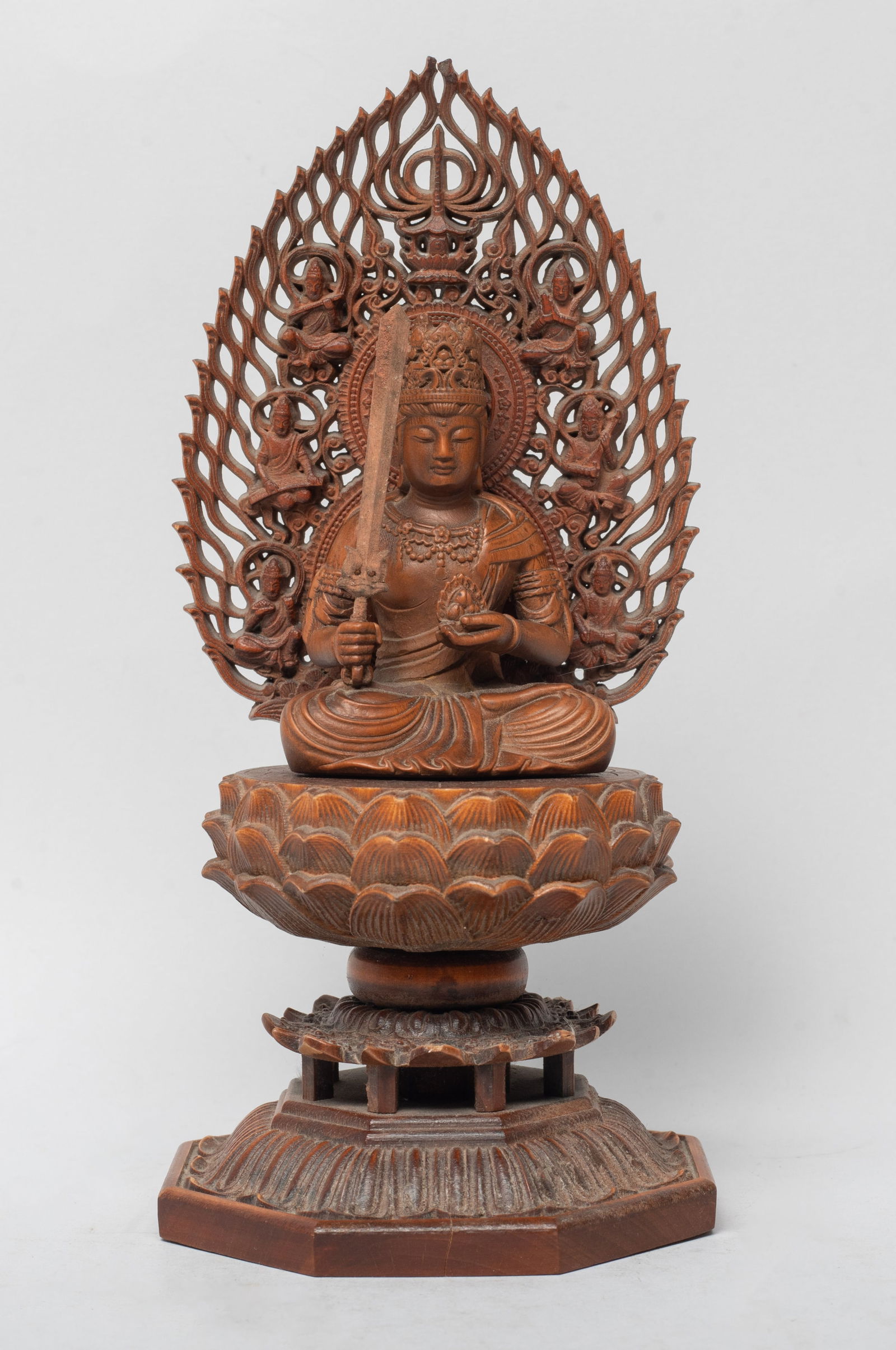 Estate Chinese Wood Sculpture of Buddha: The seated Buddha holding implements in both hands, with a tall lotus plinth, back with flame shaped mandorla and accompanied by attendant Buddha. Approx. 7*3.3*3.3 inch.
