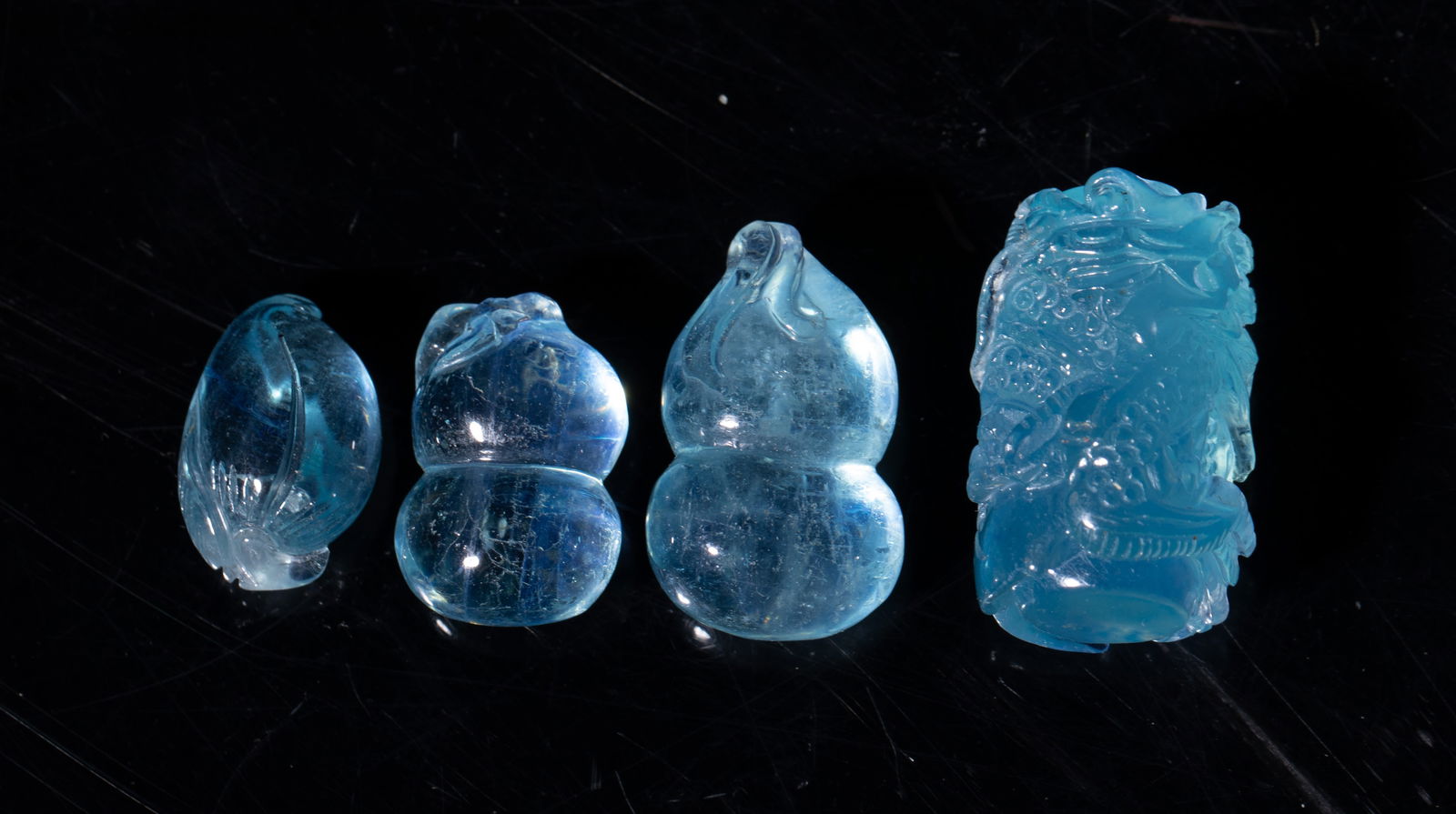 Four Chinese High Quality Aquamarine Pendants: Set of four high quality aquamarine pendants, two carved of gourd form, one of peach form, the other carved in high relief with a sinuous dragon grasping lingzhi. Approx. 32 gram (total weight),