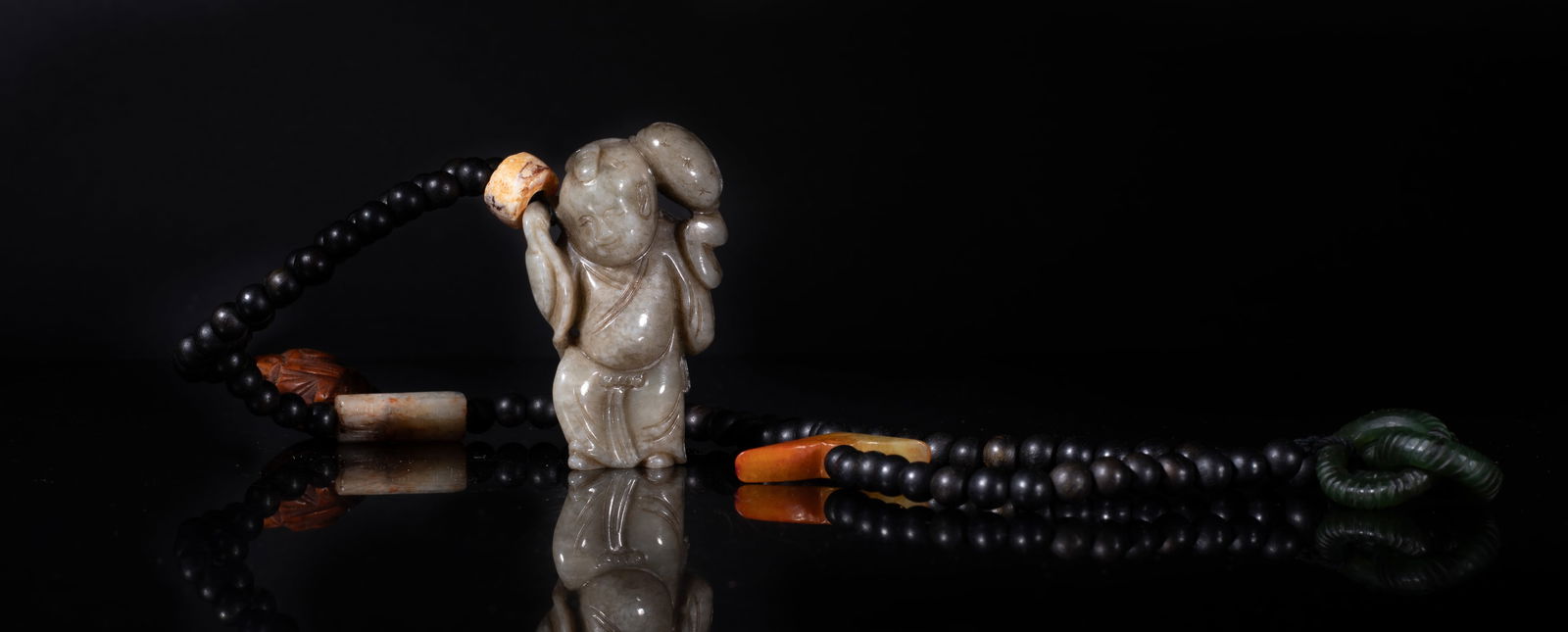 Chinese Agarwood, Jade, Carved Nut Necklace: Chinese agarwood bead necklace, with three interlocking loops, a russet jade toggle, a russet jade bead, a nut bead carved of Buddha form, an agate bead, and a jade pendant carved of boy form.