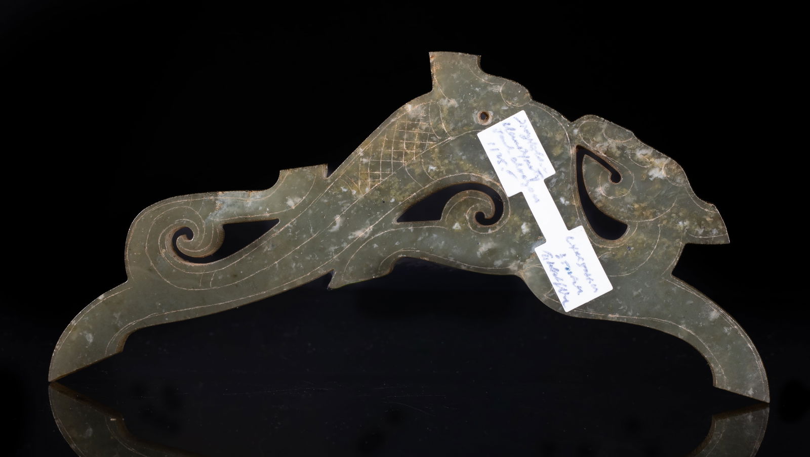 Rare Chinese Russet Jade Long Dragon Pendant: Carved in profile, the dragon depicted with almond-shaped eyes and a prominent snout, the curled body terminating in a forked tail, the translucent stone of mottled celadon tone. Approx. 5.7*1.8 inch.