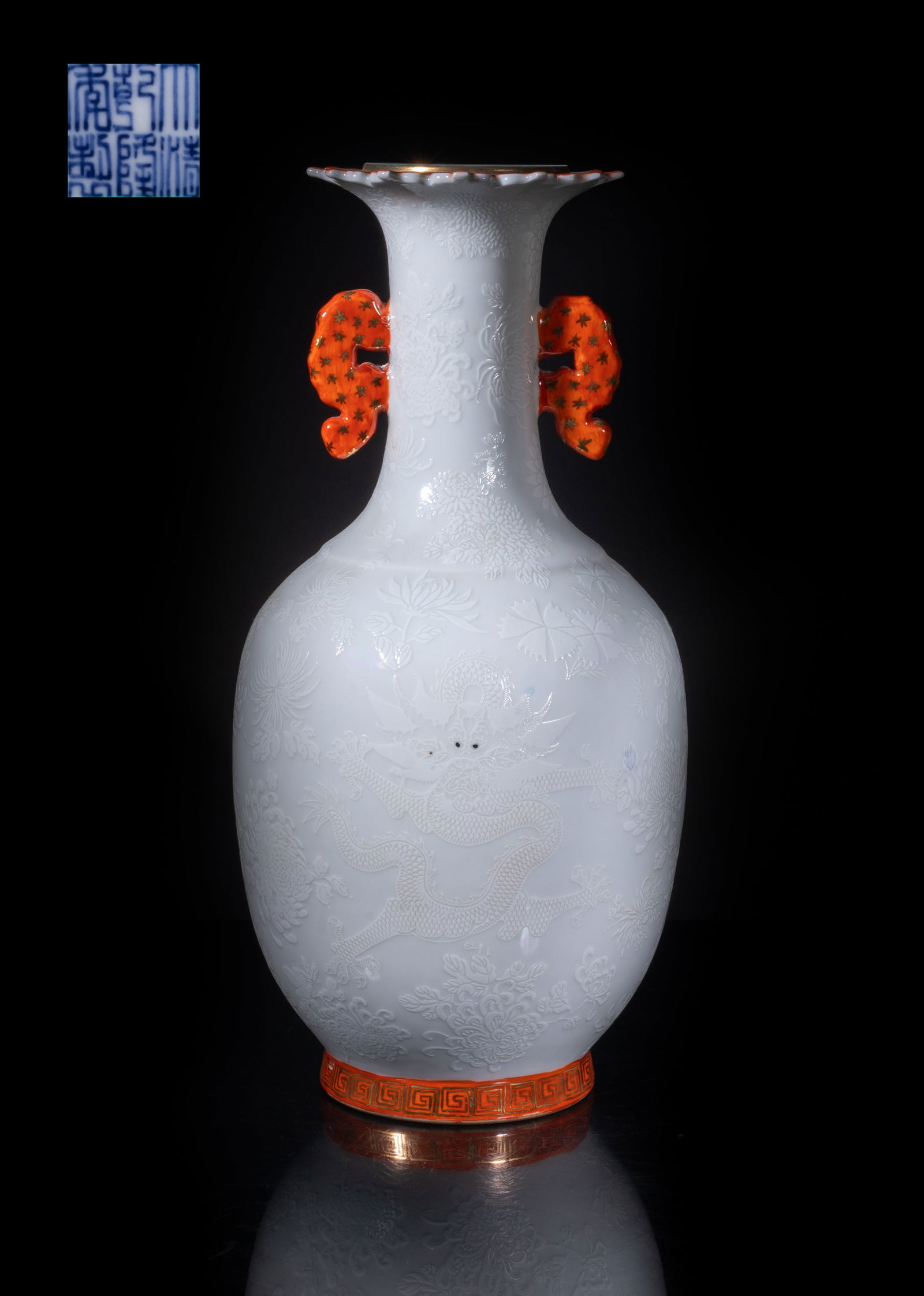 Tall Chinese Export Porcelain Dragon Vase: The ovoid body rising from a short foot to a cylindrical neck with floral form rim, flanked by two handles at the neck, the white glazed exterior carved in low relief with dragons sinuous amongst