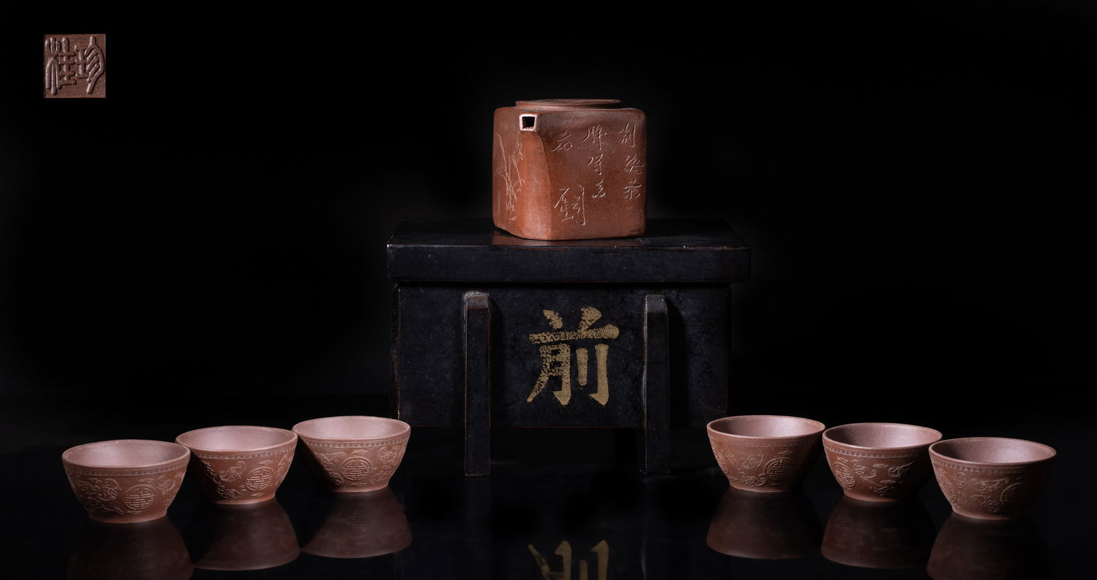 Chinese Export Yixing Zisha Tea Set: Set of one zisha tea pot and six tea cups, the tea pot incised with orchid and poem, the bottom with a seal mark, each tea cup exterior carved with bats and shou characters among clouds, the bottom wi
