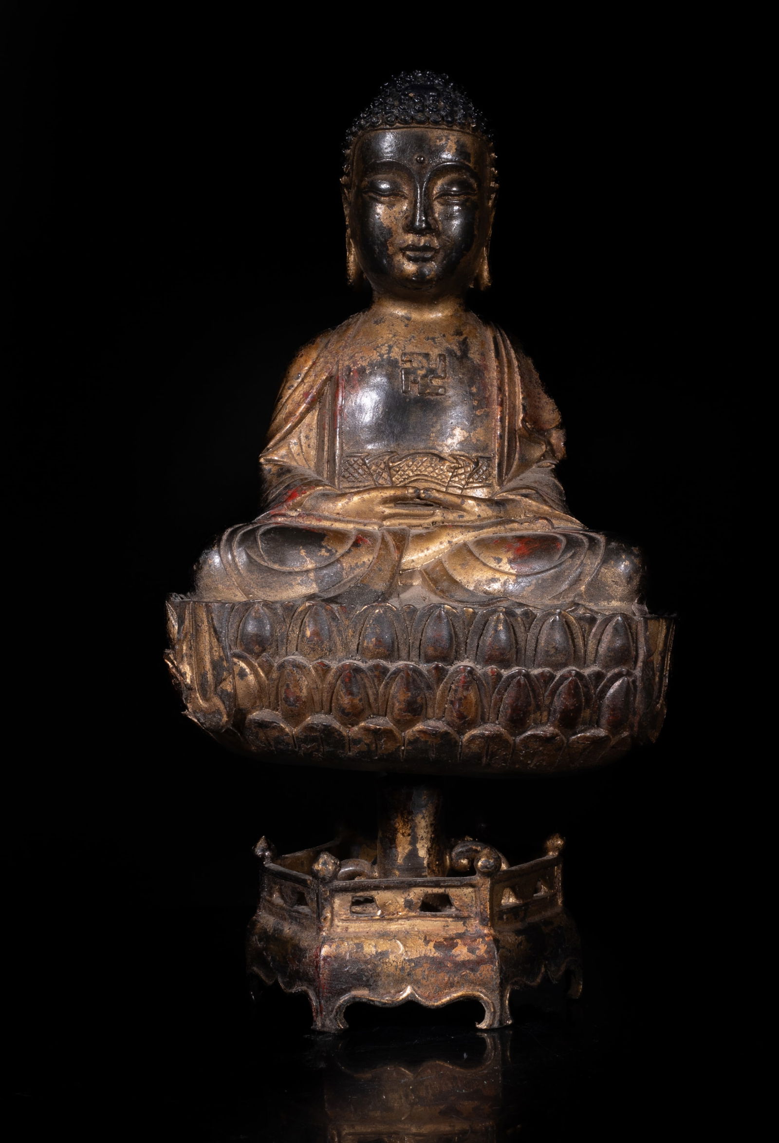 Estate Chinese Gilt Bronze Sculpture of Buddha: The Buddha cast seated in dhyanasana, wearing a loose-fitting robe open at the chest revealing a swastika symbol, the hands in dhyana mudra, with a lotus throne and a plinth of hexagonal section. Appr