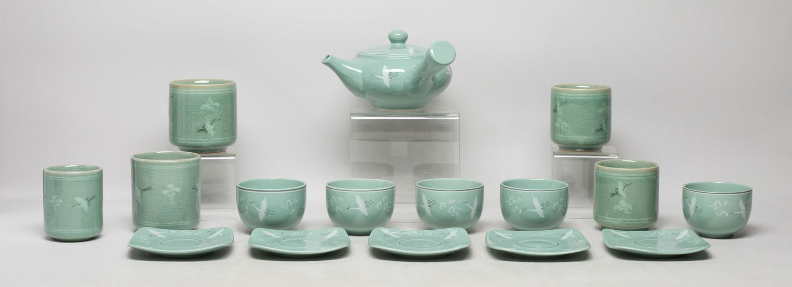 Estate Set Korean Porcelain Tea Wares: Set of Korean porcelain tea service pieces, including a tea pot, tea cups and saucers, decorated with cranes flaying amongst clouds on celadon glazed body. Size varies.