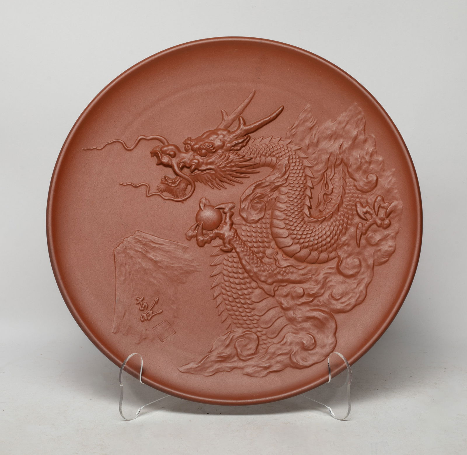 Vintage Japanese Clay/ Porcelain Dragon Charger: Carved with a sinuous dragon grasping a ball in its paw, the bottom inscribed with a circular mark. Approx. 11.5 inch D.