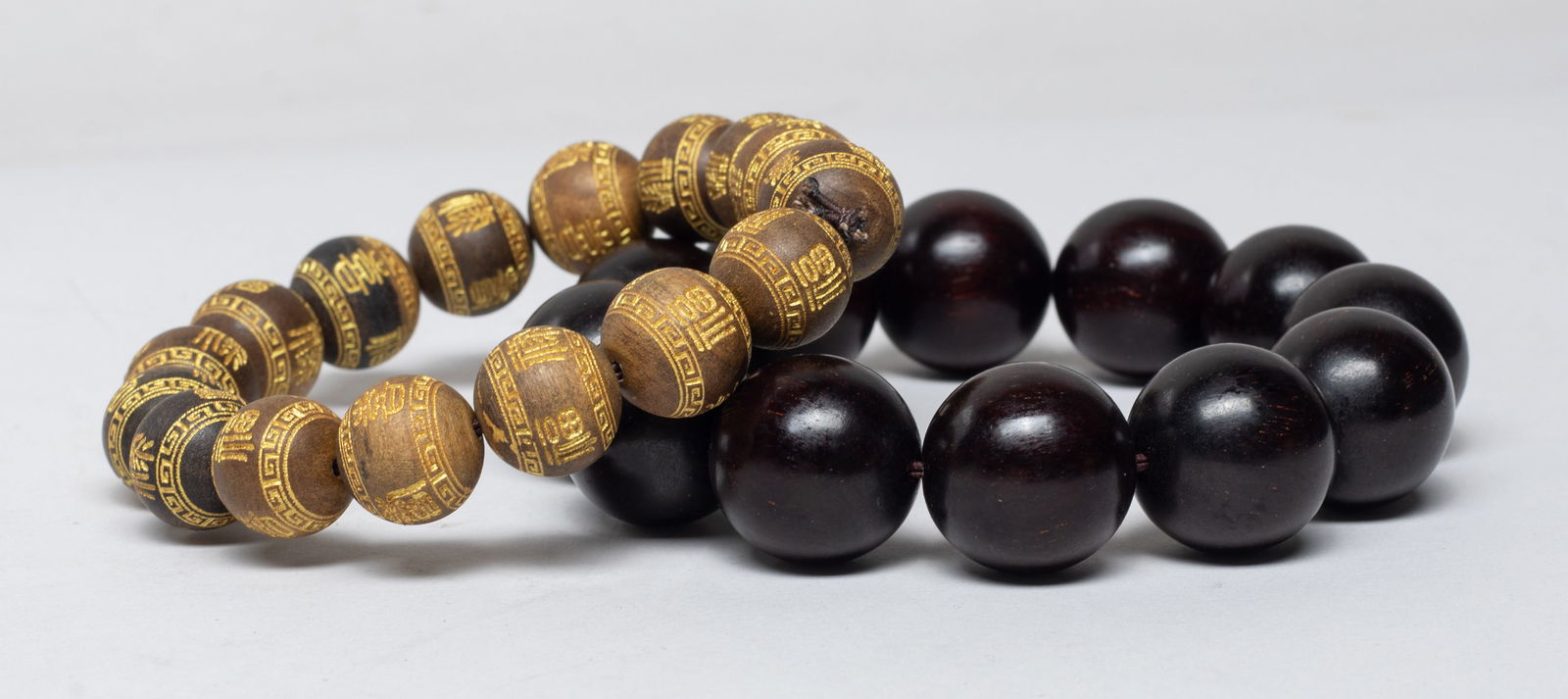Two Chinese Export Agarwood Prayer Beads: Two strings of Chinese agarwood prayer beads, the smaller beads carved with stylized characters, slightly fragrant. Approx. 0.8 inch D (larger bead size). 85 gram (total bead weight).