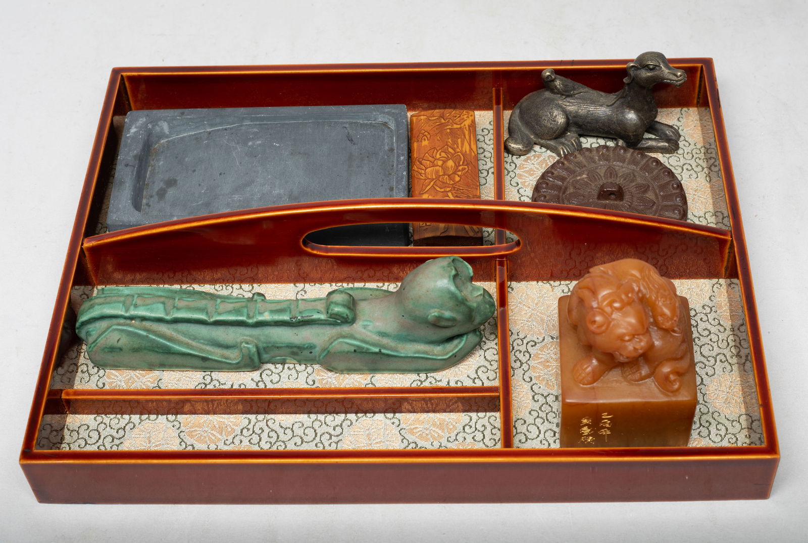Chinese Stone, Porcelain, Bronze Writing Sets: Including an ink stone, a seal, a monkey form paper weight, a wood case carved lotus, a metal sculpture cast as a recumbent dog with a bird on its back, and a metal piece cast with flower. Approx.