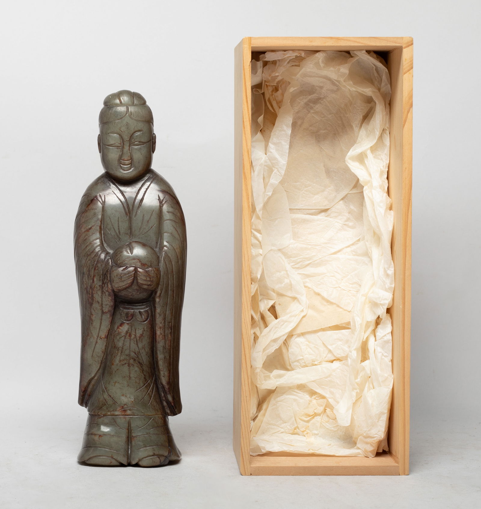 Tall Chinese Russet Jade Carved Figure: Large Chinese russet jade figurine sculpture, carved in standing pose wearing a long robe, the hands holding a peach, with a lidless box. Approx. 9.3*2.8*1.8 inch (w/o box).