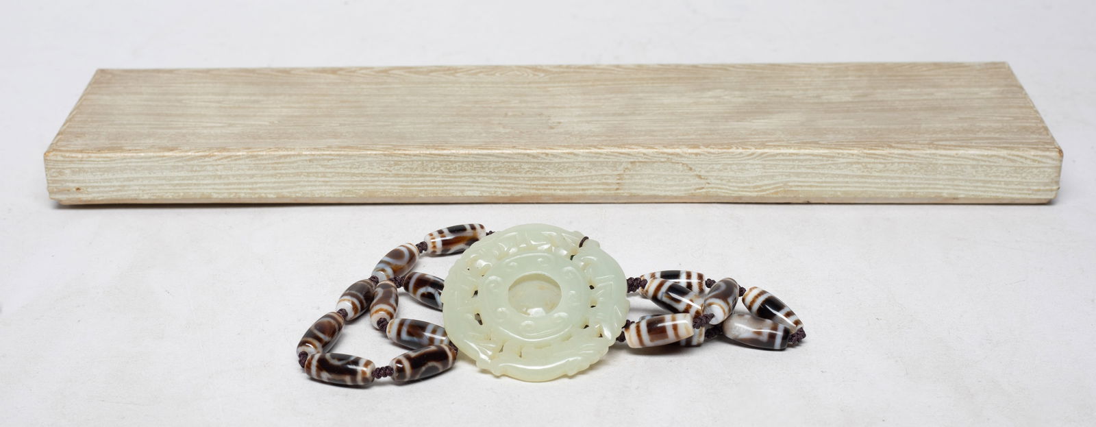 Chinese Dzi Beads Necklace w/ Jade Pendant: Chinese dzi bead necklace, suspended with a bead and a jade pendant, carved as two pairs of confronting beasts framing a circular bi with a movable center. Approx. 2.1 inch D (jade pendant size).