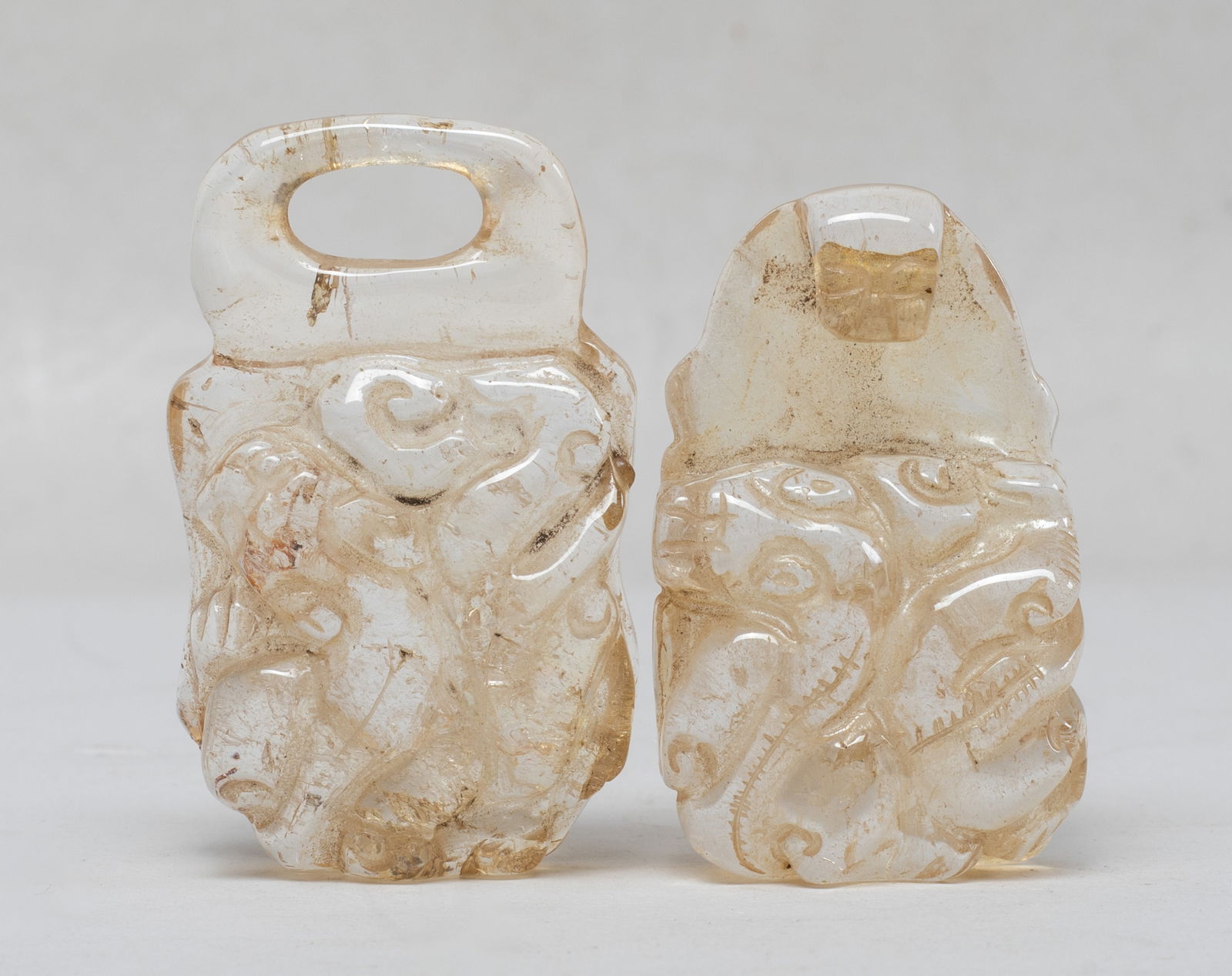 Estate Chinese Rock Crystal Belt Buckle: One half of the buckle has a dragon-head hook, the other a corresponding loop, each half with a circular button on the underside and carved in high relief on the top with a sinuous chilong. Approx.