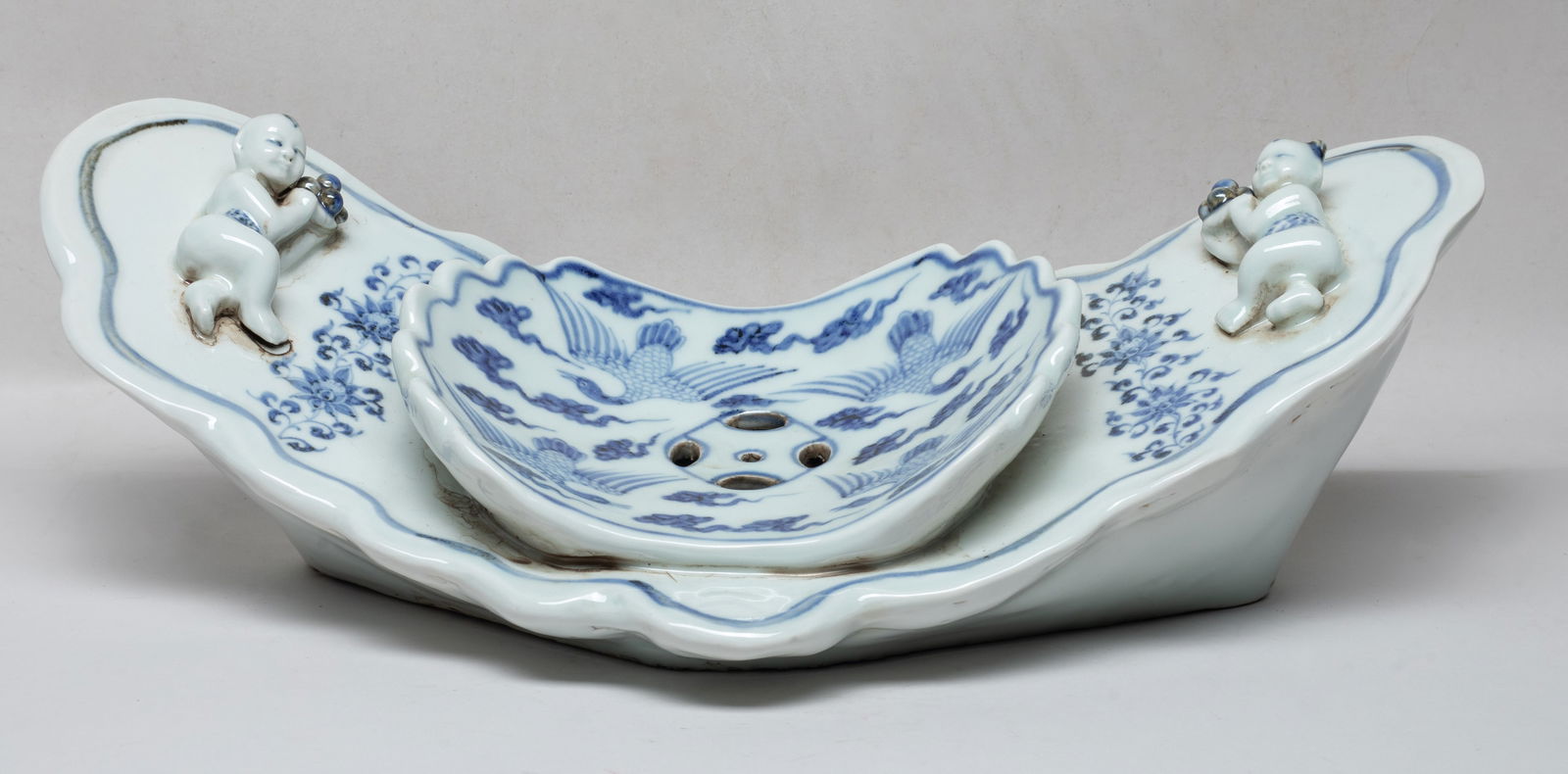 Large Chinese Export Porcelain Pillow: Special form blue and white porcelain pillow, the central panel painted with birds flying amidst clouds, the sides painted with lotus foliage and carved in high relief with boys. Approx. 17.2*7*5.5