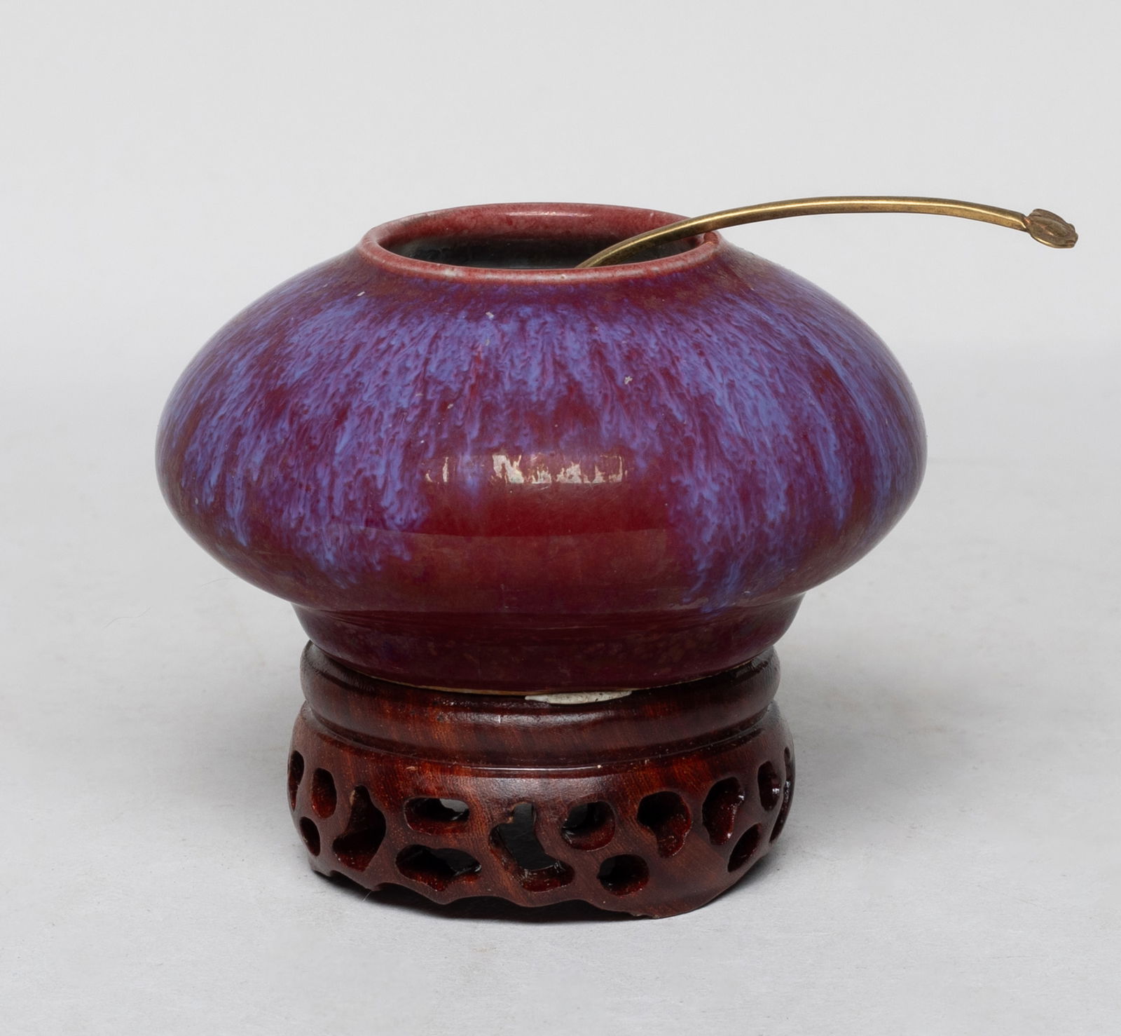 Chinese Flambe Glazed Porcelain Water Pot: Of compressed form, the washer exterior covered with rich red glaze suffused with lavender blue streaks, with a spoon, affixed to a wood stand. Approx. 3.4*2.8 inch (w/ stand).
