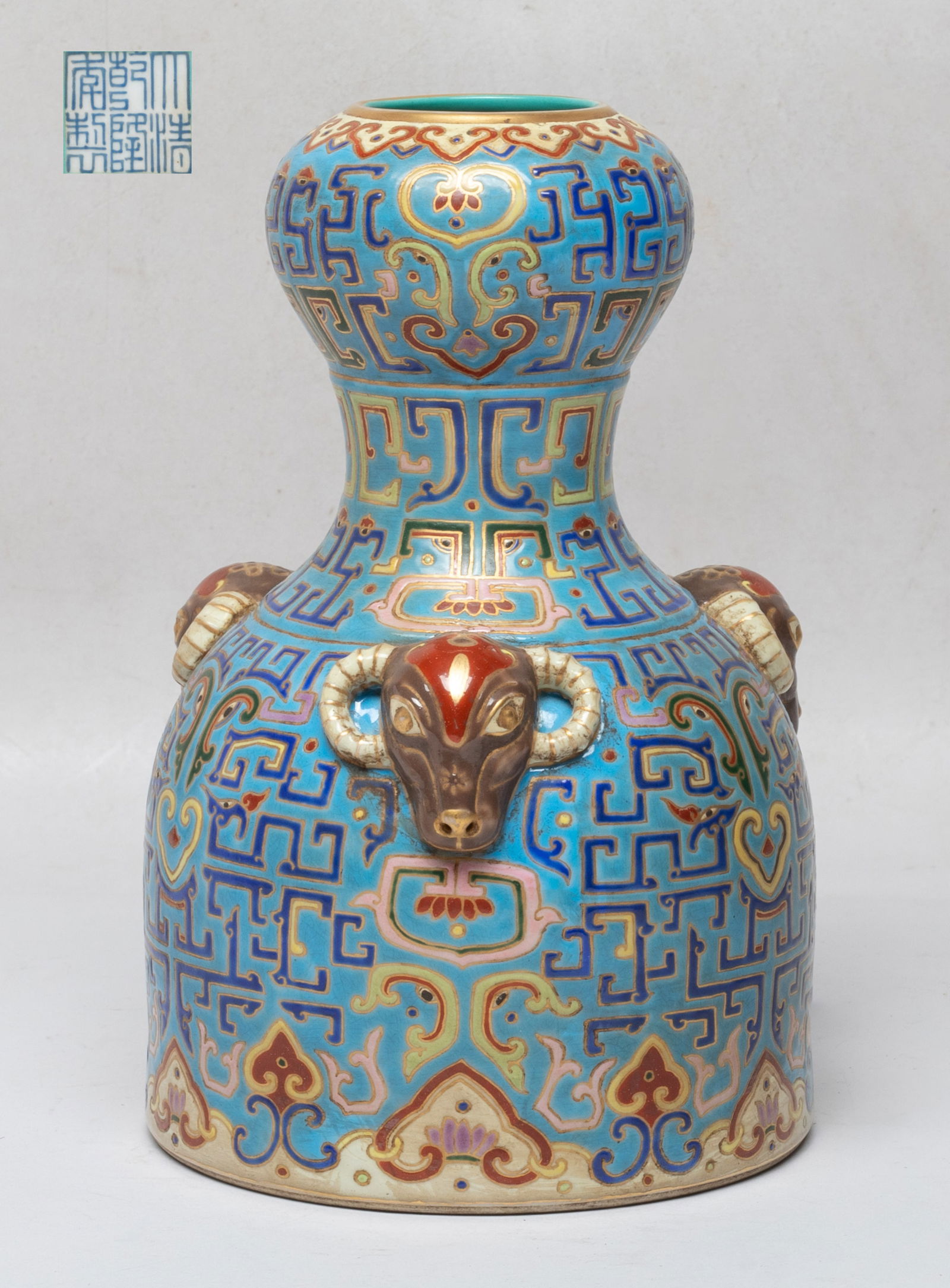 Chinese Enameled Porcelain Cabinet Vase: The vase exterior enameled with archaistic beasts and masks on blue glazed ground, between bands of ruyi heads, flanked by three raised goat masks, the interior and the bottom turquoise glazed, a
