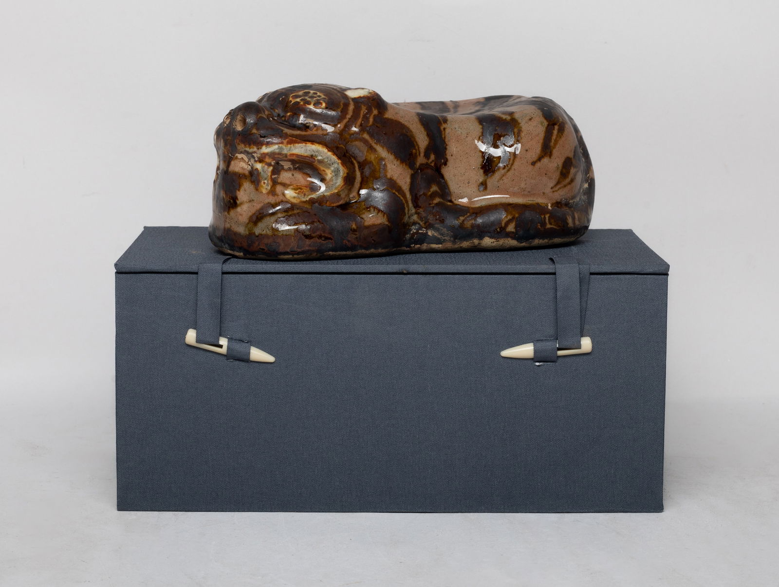 Chinese Glazed Stoneware Arm Pillow: Moulded of recumbent beast form, applied with mottled soft and dark brown glaze, save for the unglazed bottom, drilled at the nose and haunch, with box. Approx. 6.8*3.4*2.6 inch (pillow size).