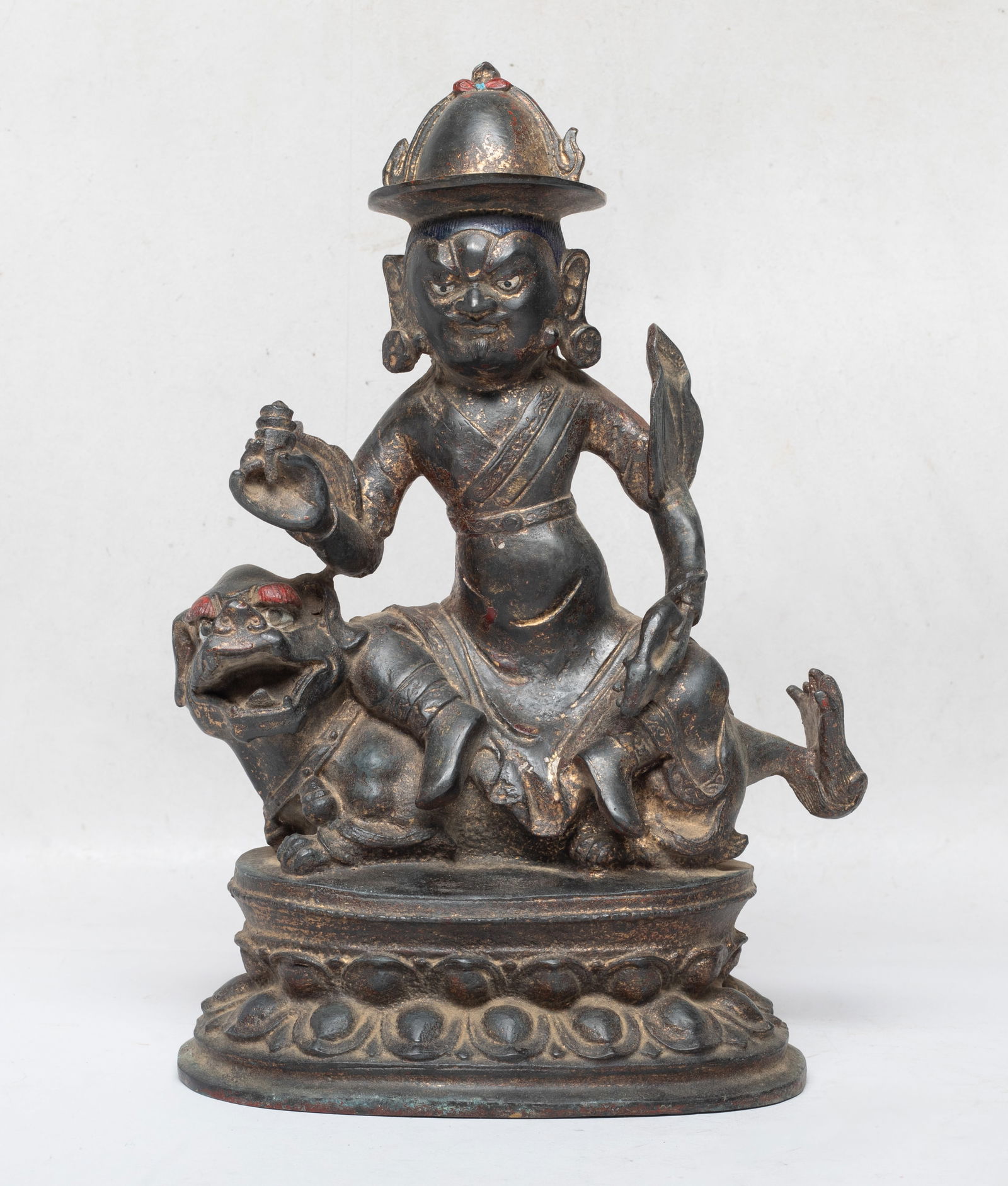 Estate Chinese Export Bronze Buddha: The Buddha cast sitting on a recumbent beast on a waisted lotus base, the beast head turned to the left, his left hand holding a mouse and right hand holding a conch shell, wearing a tall hat. Approx.