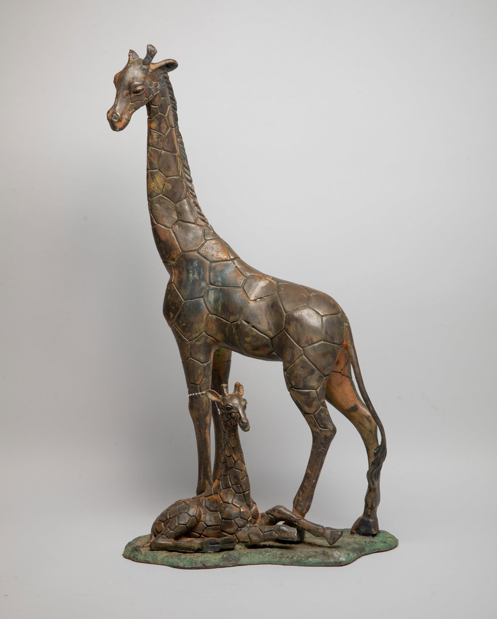 Large Painted Metal Sculpture of Giraffe: Large room decor painted metal sculpture, moulded as a standing giraffe with its head slightly turned to the left, its cub recumbent around its legs. The giraffe's horn and the cub's leg broken. Appro
