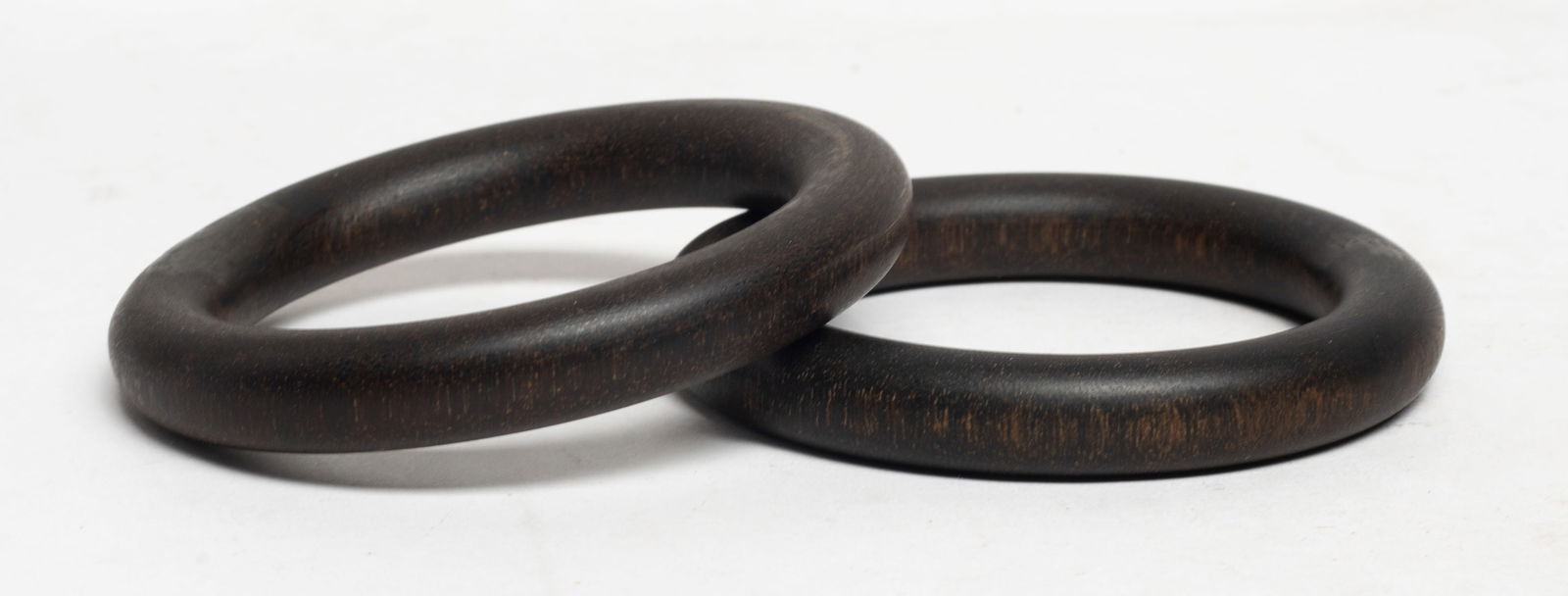 Two Chinese Export Agarwood Bangles: Two Chinese export agarwood bangles. Approx. 61 gram (total weight), 3.33 inch outer diameter, 2.27 inch inner diameter (larger bangle). The Estate of S Pasadena, CA, 2024.