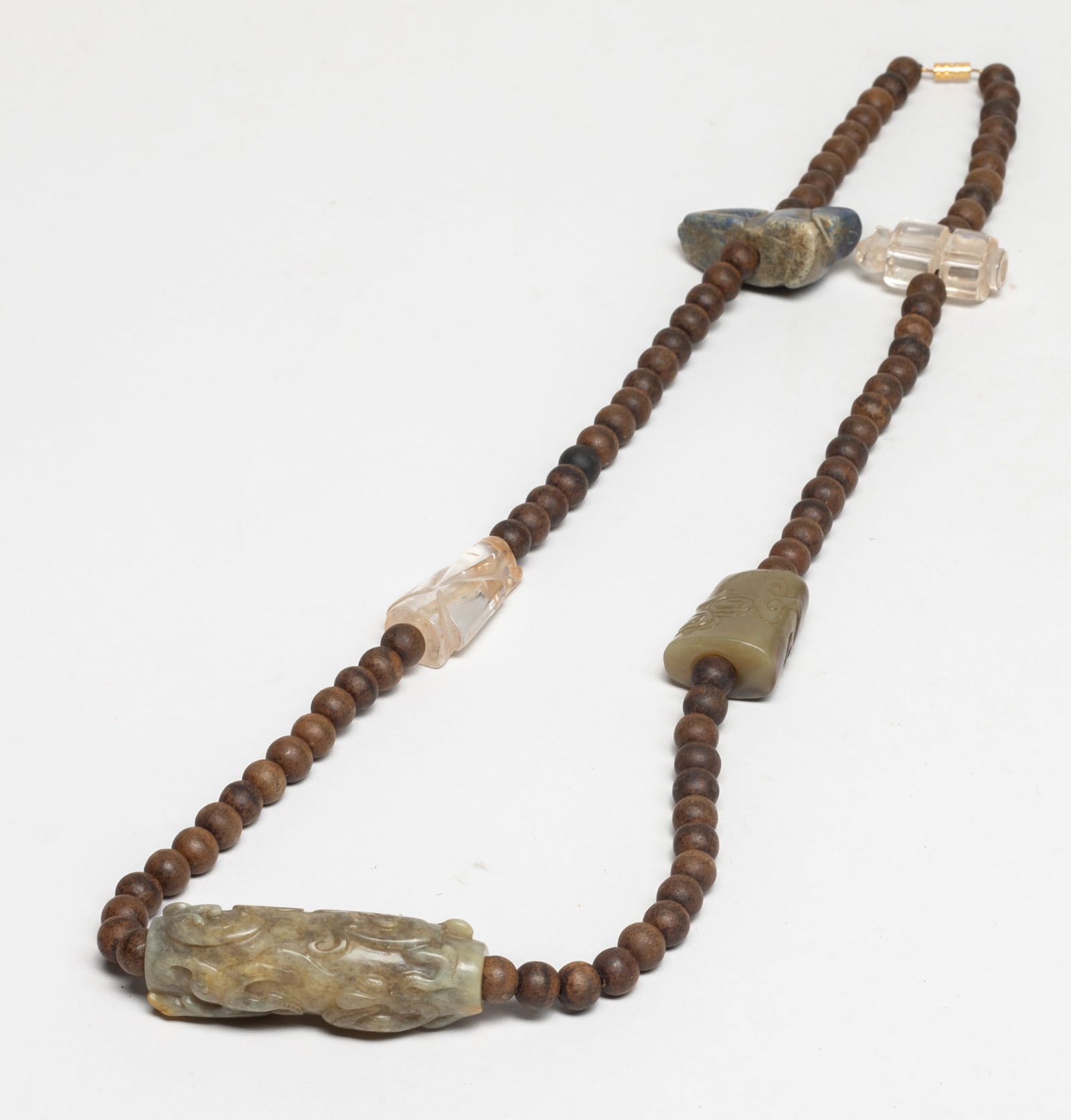 Chinese Export Jade, Agarwood, Stone Necklace: Chinese agarwood bead necklace, with a beast form stone toggle, two jade toggles carved with archaistic beasts or beast & lingzhi & clouds, and two crystal toggles carved of figure or traditional jade