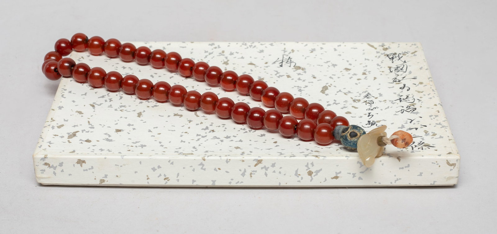 Rare Chinese Cameo Agate, Jade Prayer Beads: A string of Chinese cameo agate prayer beads, finely polished, suspended with glass beads, stone beads, and a jade toggle of beast form, with box. Approx. 16 inch L (string size). The Estate of the St