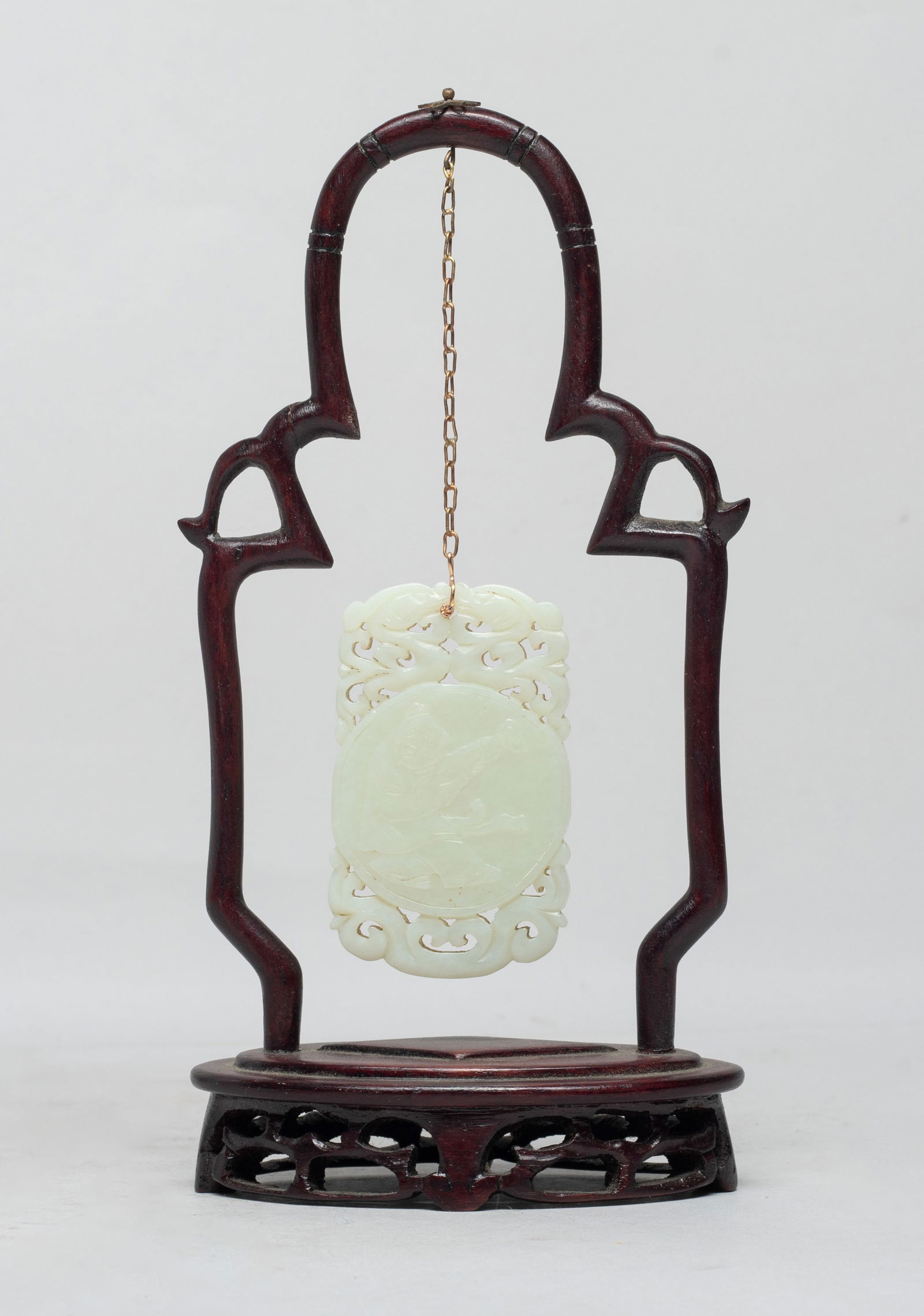 Chinese Jade Plaque w/ Wood Stand: One side carved with a figure holding a ruyi, the reverse with a seal mark, surmounted by a pair of confronting dragons, suspended on a wood stand. Approx. 2.7*1.6 inch (jade size). The Estate of S Pa