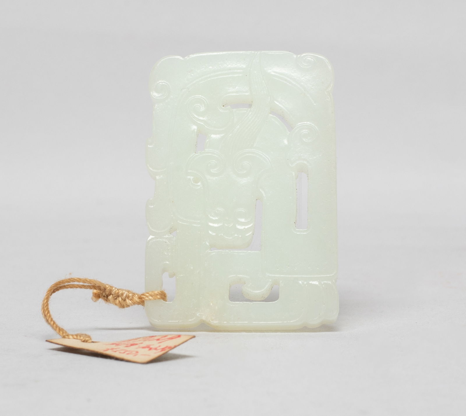 Estate Chinese Export White Jade Pendant: The flat pendant shape finely carved and reticulated as a dragon shown in profile with a sinuous body and a curling tail. Approx. 2.05*1.4 inch. The Estate of the F. C. Chung. SF. 2012.