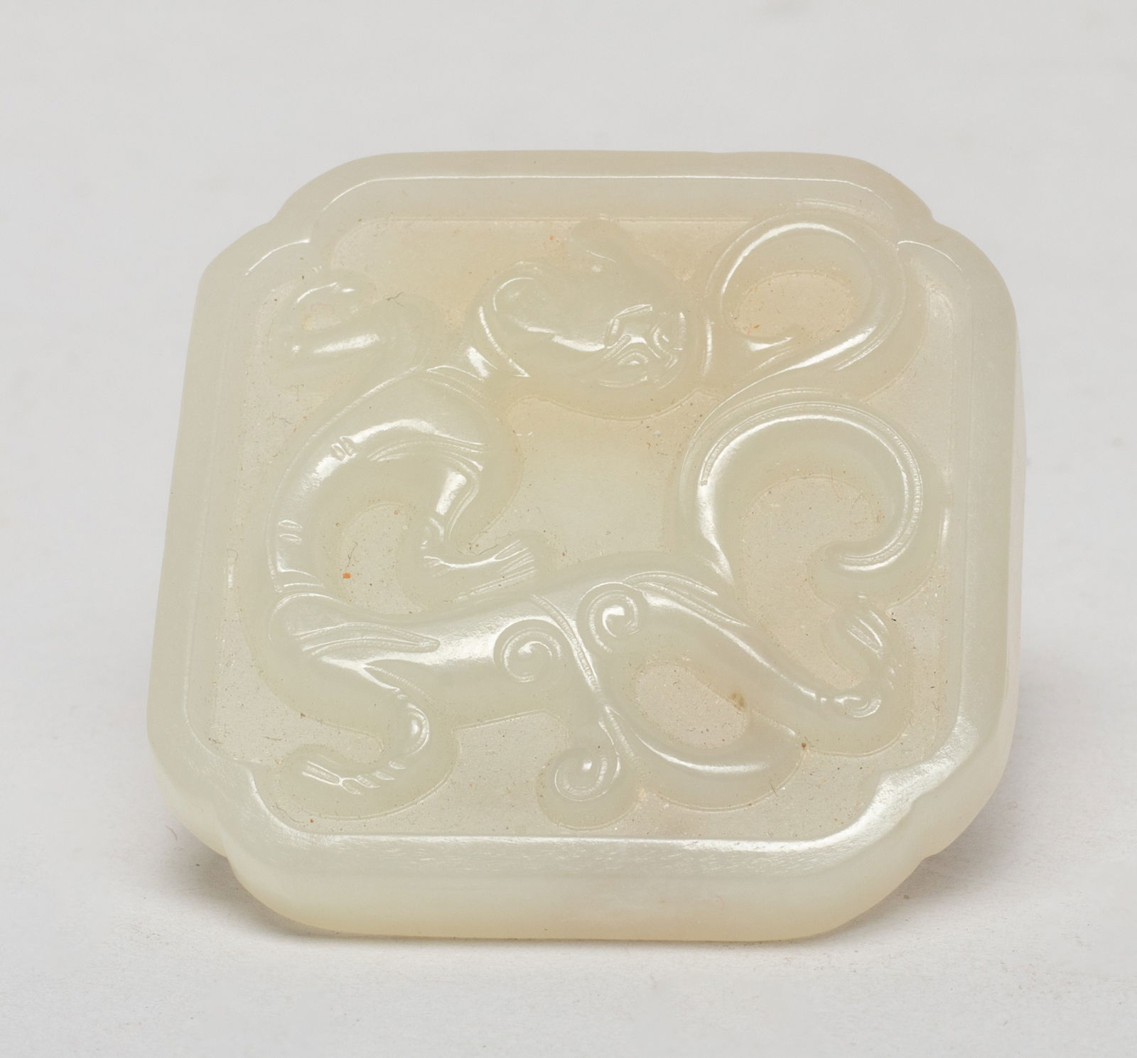 Chinese White Jade Belt Plaque: Of circular shape, one side carved in raised relief with a sinuous archaistic beast. Approx. 1.9*1.9 inch.