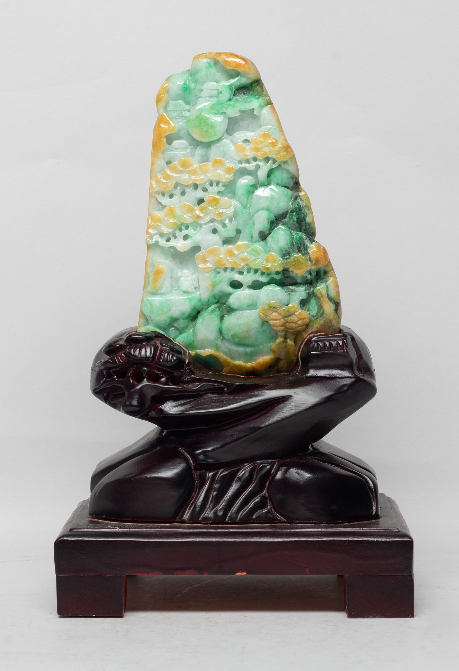 Chinese Export Jade Sculpture: Carved in varying levels of relief as a craggy mountainscape encompassing scattered pine trees and distant pavilions, a scholar and a boy standing under the trees, the stone various of shades of green