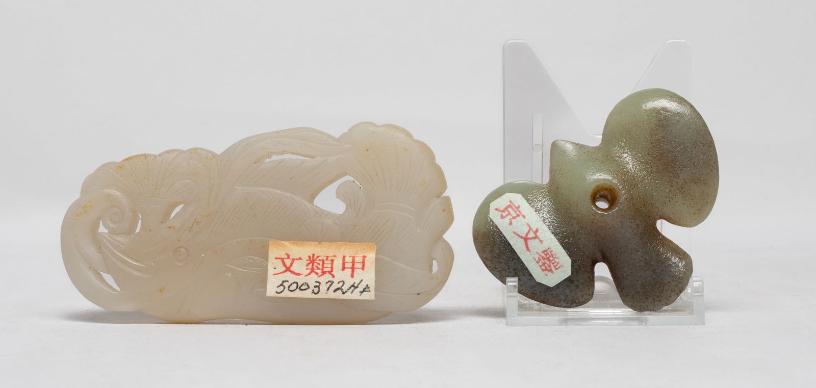 Two Chinese Export Jade Pendants: One carved as a bird, pierced at the body centre, the other formed as a fish holding a long stem and a leaf in its mouth. Approx. 4*2*0.47 inch (larger)/ The Estate of the F. C. Chung. SF. 2012.