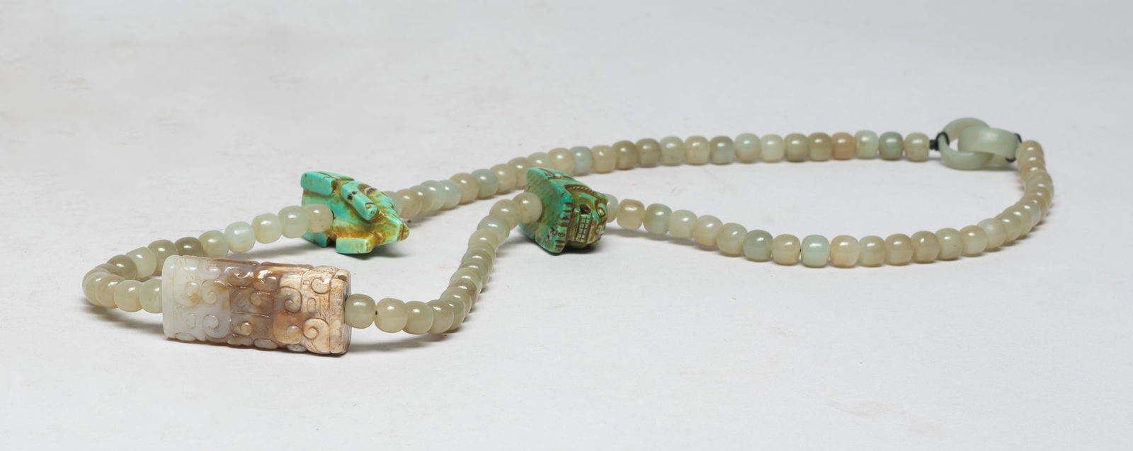 Estate Chinese Jade, Stone Necklace: Chinese jade bead necklace, with a russet jade pendant carved with archaistic beasts, and two stone pendants carved of recumbent beast shape. Approx. 27 inch L. The Estate of S Pasadena, CA, 2023.