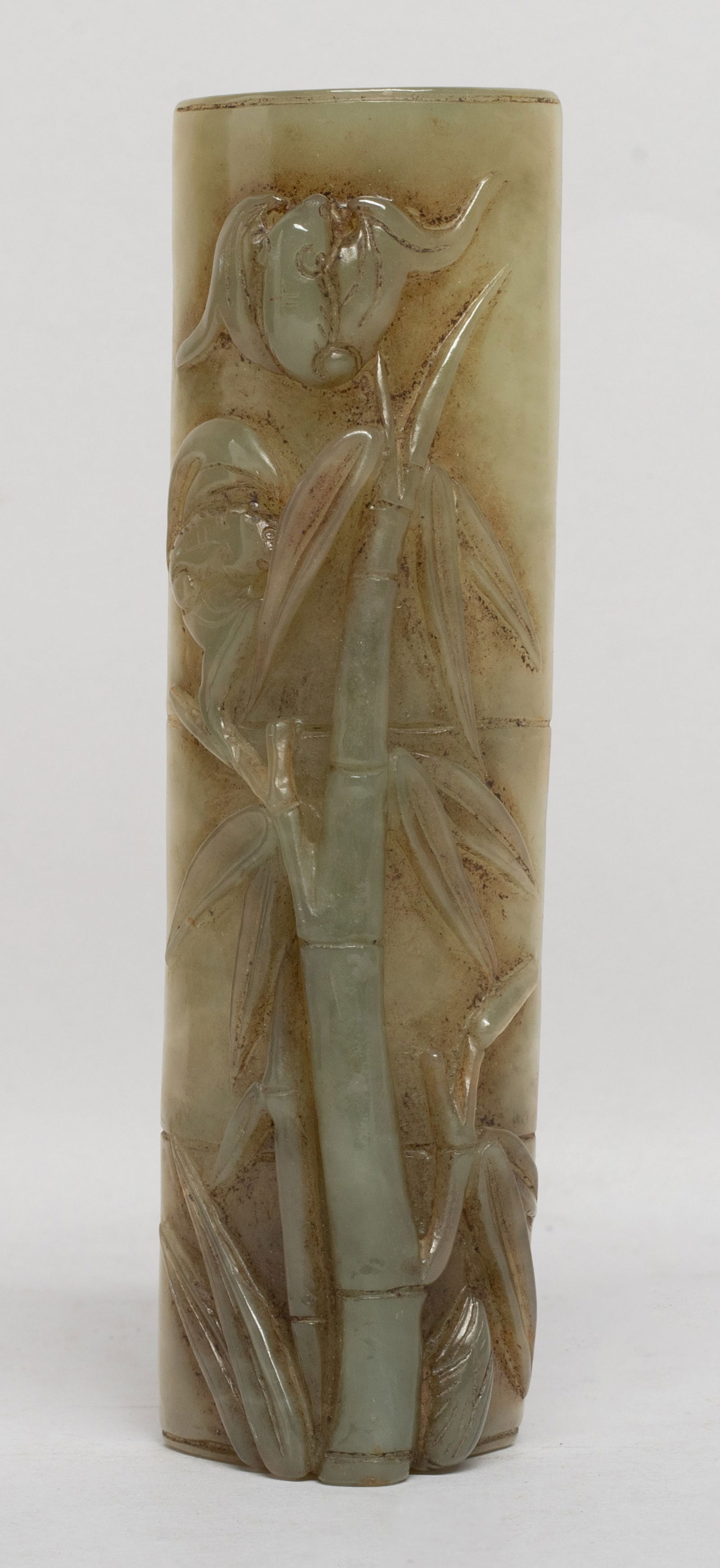 Long Chinese Jade Carved Arm Rest: Chinese jade arm rest of bamboo form, carved in high relief with bamboo stem and leaves, and a pair of bats. Approx. 5.1*1.45*0.9 inch. The Estate of E Los Angeles, CA. 2022.