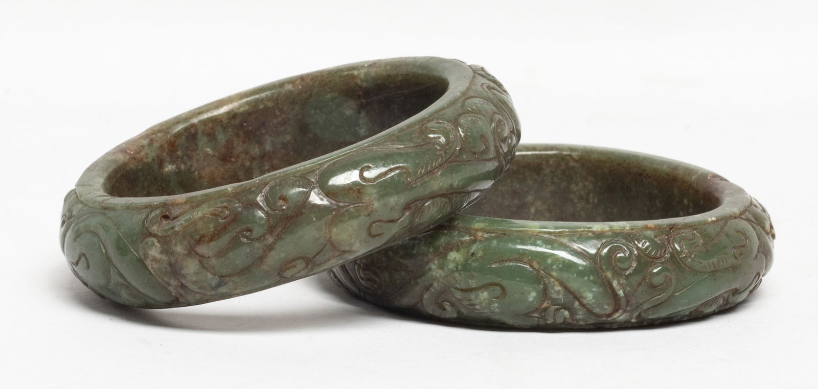 Two Chinese Carved Jade Bangles: Two Chinese jade bangles, the exterior carved with archaistic beasts. Approx. 3.15 inch outer diameter, 2.35 inch inner diameter (each0. The Estate of S Pasadena, CA, 2024.