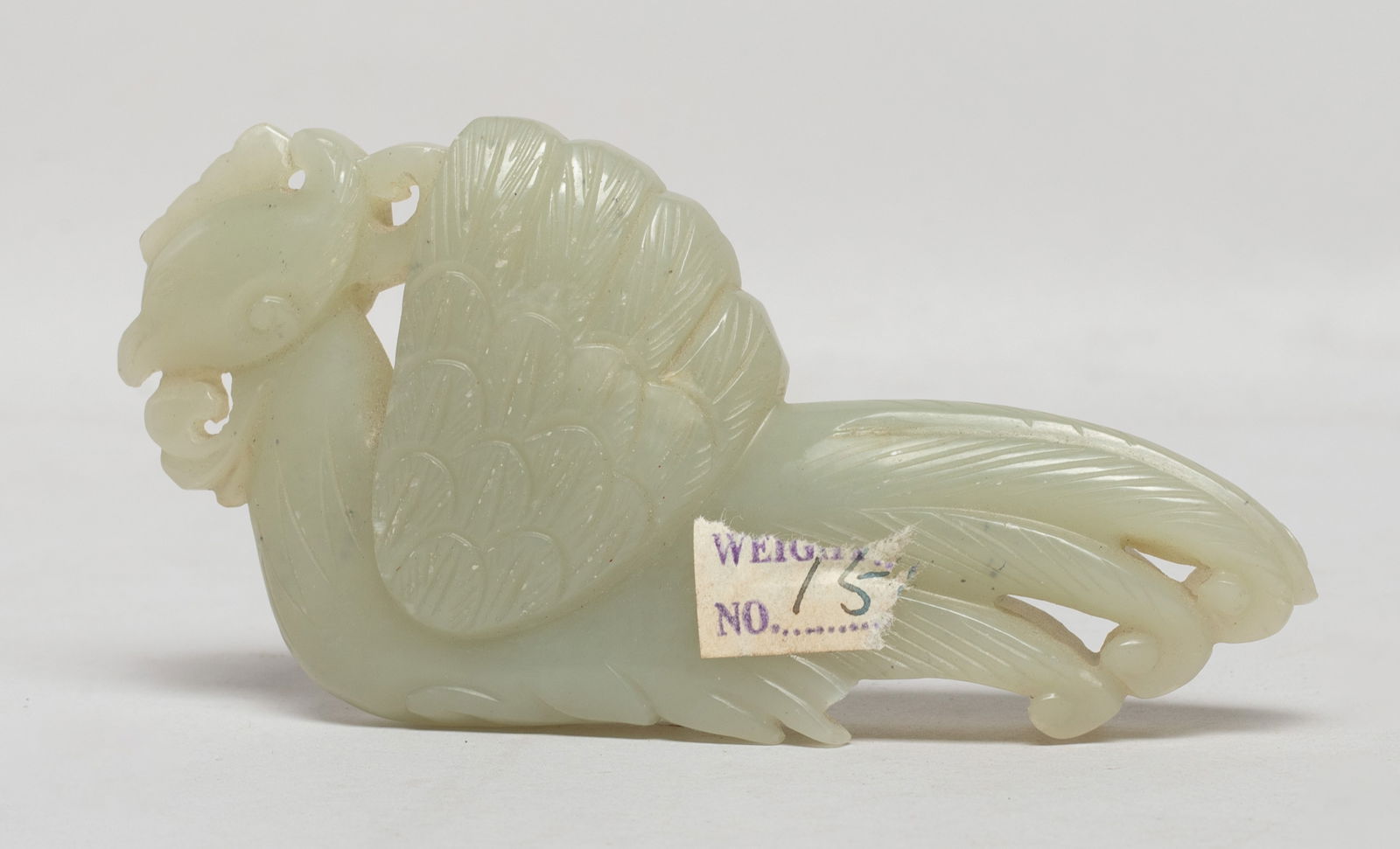 Chinese Jade Carved Pendant of Bird: Of archaistic appearance, the head surmounted by a coxcomb, detailed with incised feathers forming the wing and tail plumage. Approx. 3.97*2*0.56 inch. The Estate of E Los Angeles, CA. 2022.