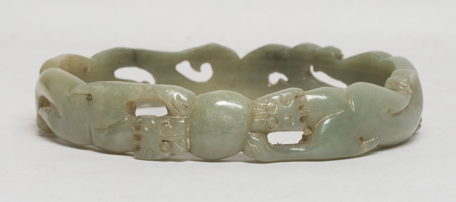 Large Chinese Jade Carved Bangle: The large jade bangle carved in openwork as a pair of confronting beasts carrying a ball. Approx. 3.64 inch outer diameter, 3.17 inch inner diameter. The Estate of S Pasadena, CA, 2024.
