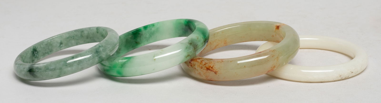 Vintage Chinese Export Jade Bangles: Set of four Chinese jade / stone bangles. Approx. 2.97 inch outer diameter, 2.2 inch inner diameter (largest). The Estate of S Pasadena, CA, 2024.