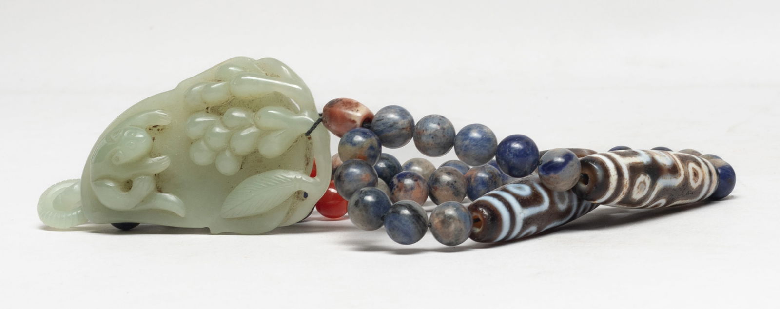 Chinese Jade, Lapis, Dzi Beads Necklace: Chinese lapis bead and dzi bead necklace, suspended with a jade toggle carved with a squirrel facing grapes, all over a leaf. Approx. 2.65*1.75*0.65 inch (jade size). The Estate of Store Moving Sale,