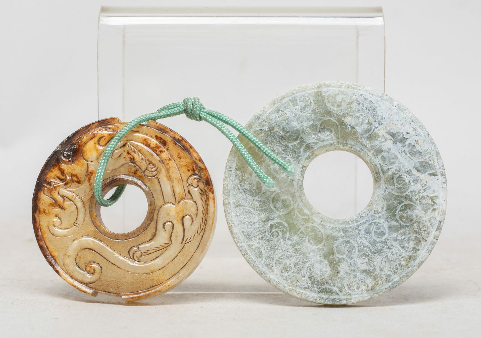 Two Chinese Jade Carved Pendants of Bi: One bi incised on both sides with scrolls, the other bi carved on both sides with a sinuous chi dragon. Approx. 2.3 inch D (larger). The Estate of the Consignment Store Closed Sale, Palm Springs, CA,