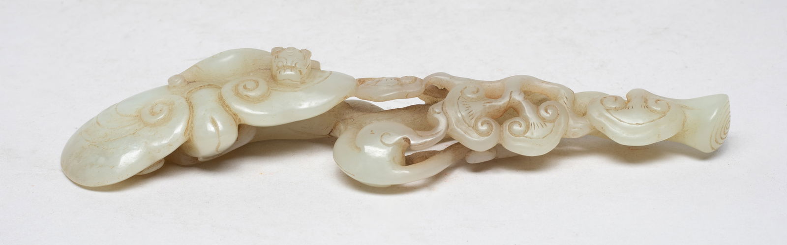Chinese Cream White Jade Sculpture of Ruyi: Naturalistically carved as a lingzhi fungus with a large lingzhi head terminal, the slender shaft in the form of a gnarled stem adorned with small lingzhi heads, a beast recumbent on the head. Approx.