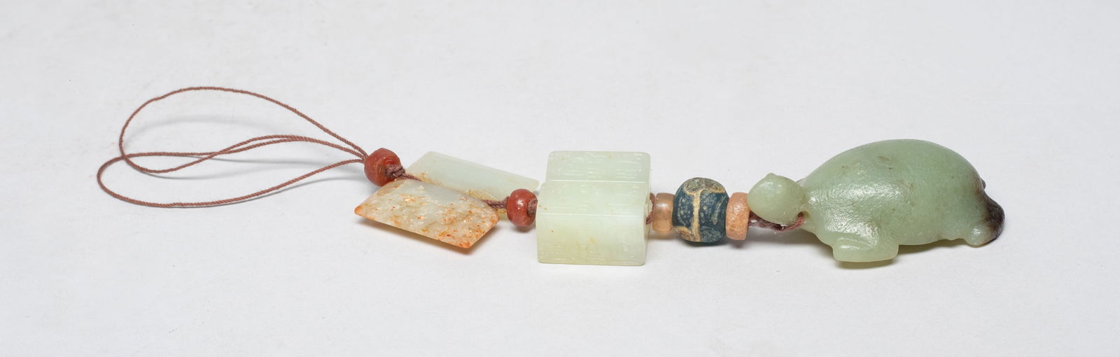 Chinese Manchu Jade Pendant: Comprised of a jade pendant carved of turtle form, two jade beads incised with characters, a russet jade pendant, and five glass / stone beads. Approx. 2.25*1.35*0.65 inch (largest pendant). The Estat